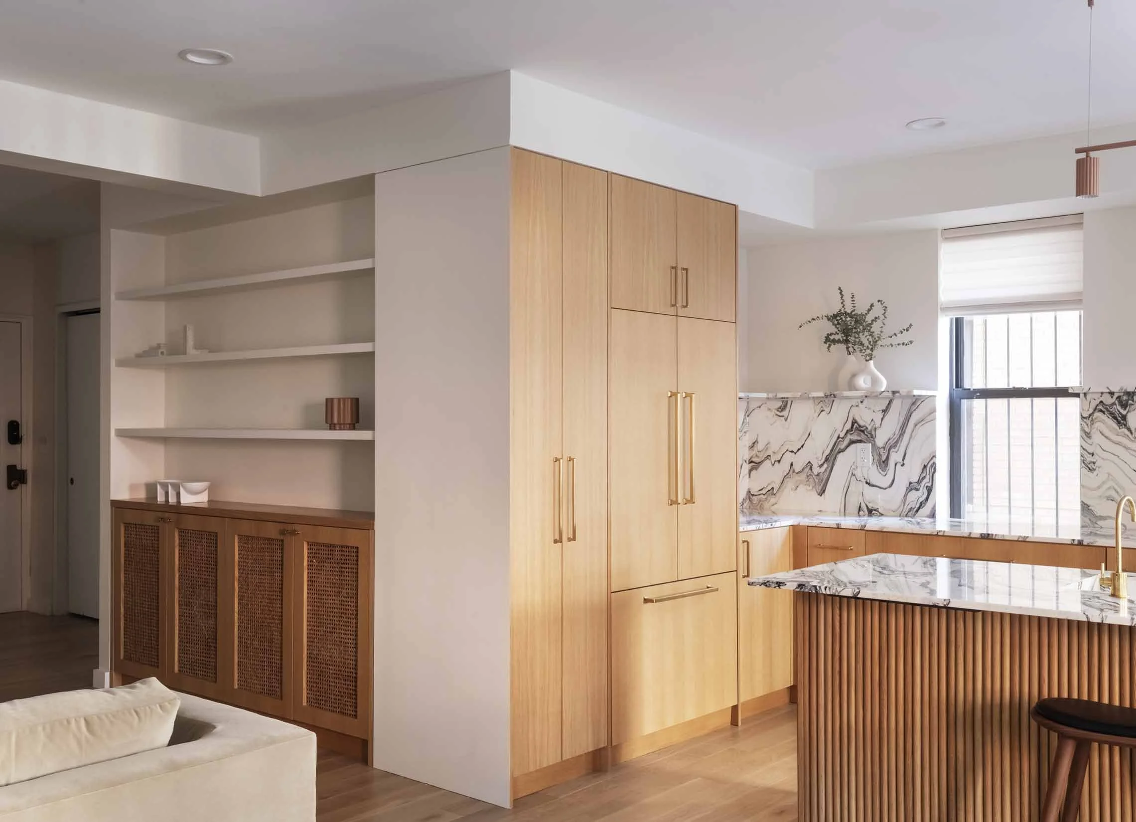 Modern kitchen with wooden cabinets, marble backsplash, and open shelving in a light and airy space.