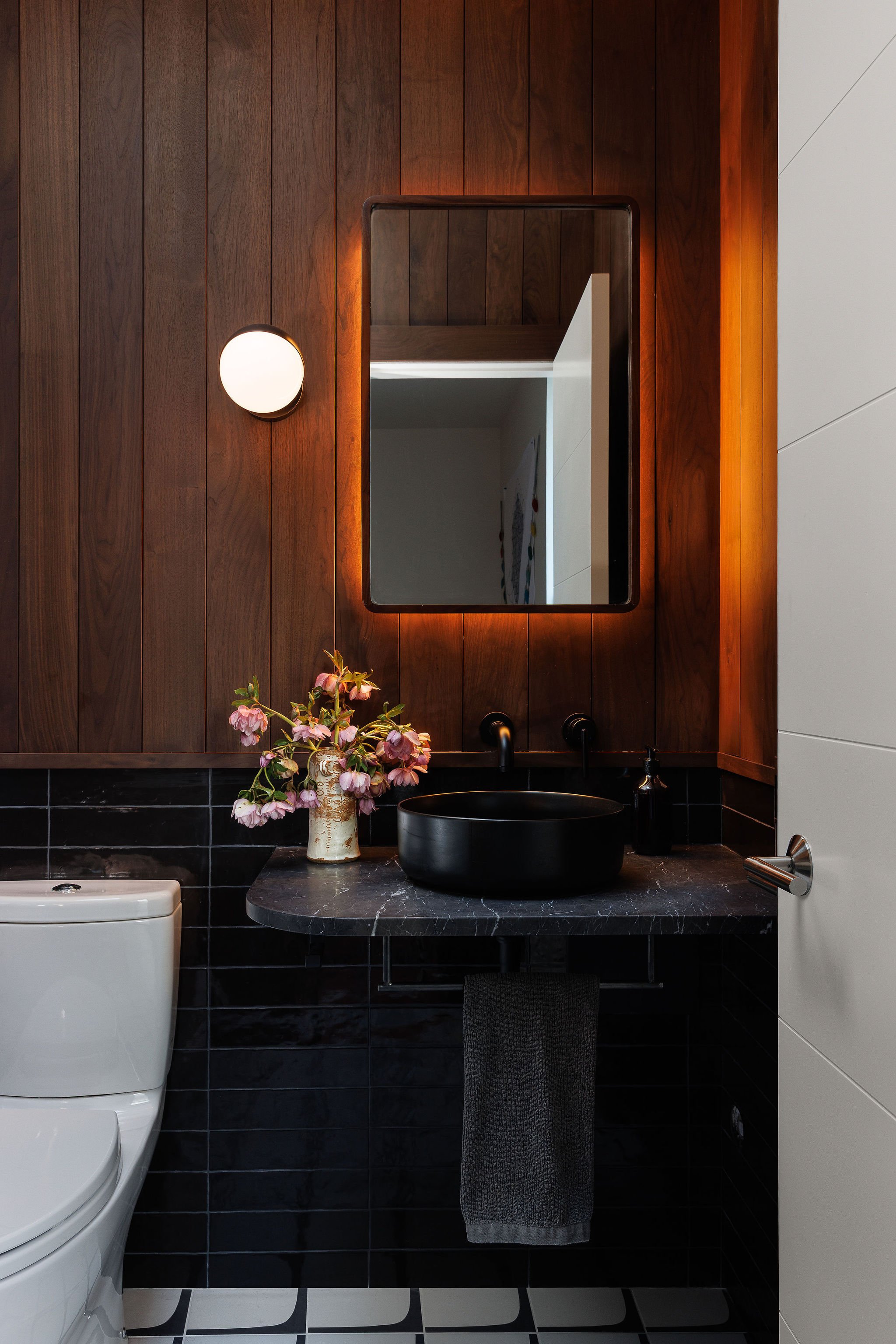 Residential powder room featuring walnut wall paneling and a floating black stone vanity in Victoria BC by Little Giant