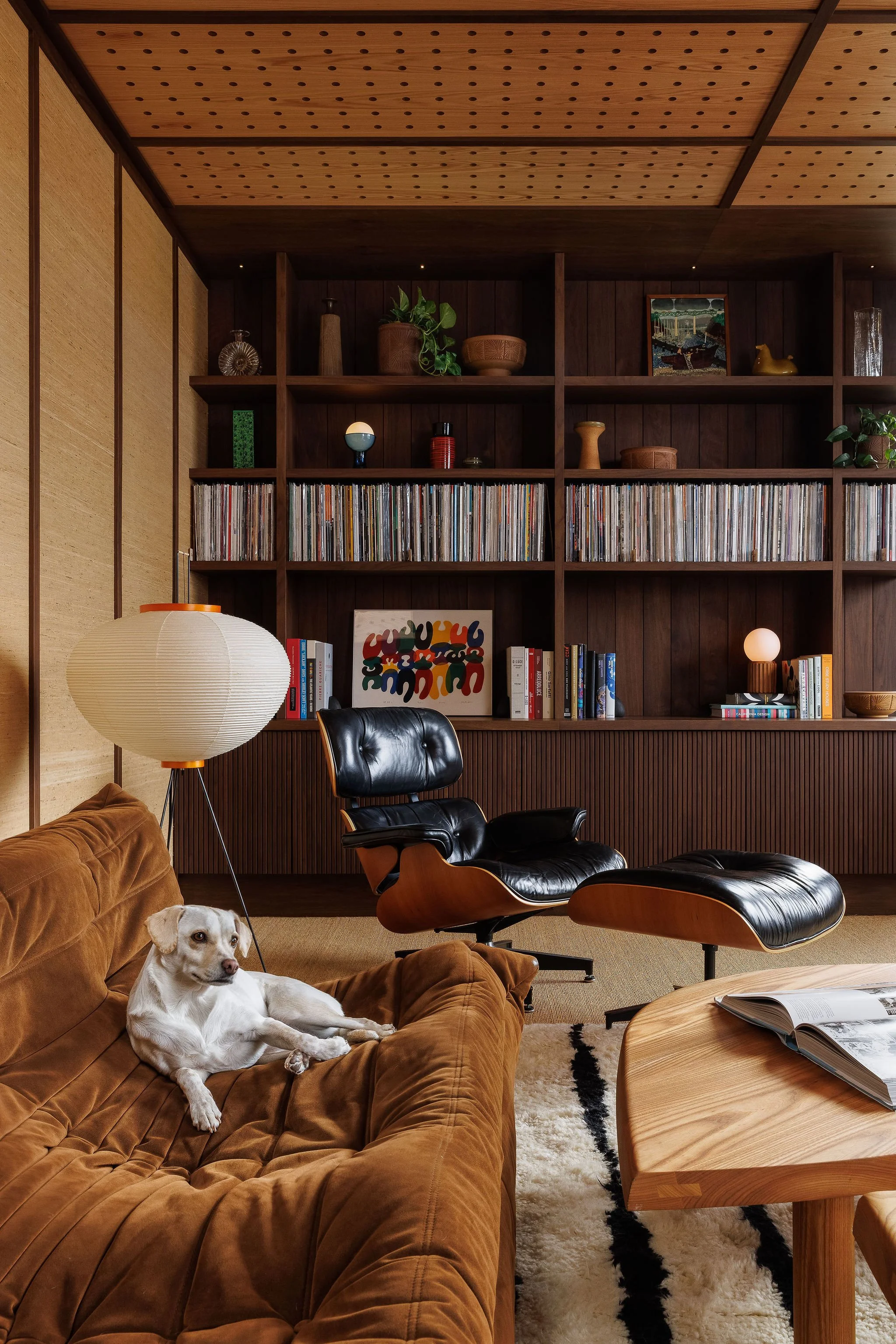 Residential listening lounge with custom walnut shelving, integrated record storage, and a lounging dog in Victoria BC by Little Giant