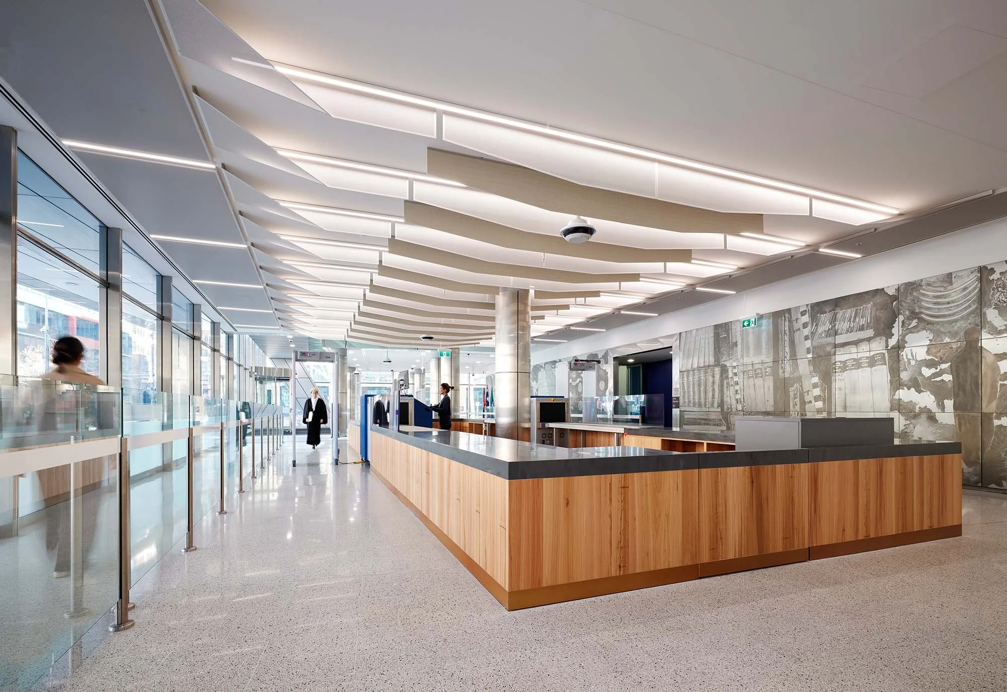 Court foyer looking along glazed facade, with security checkpoint and mural wall