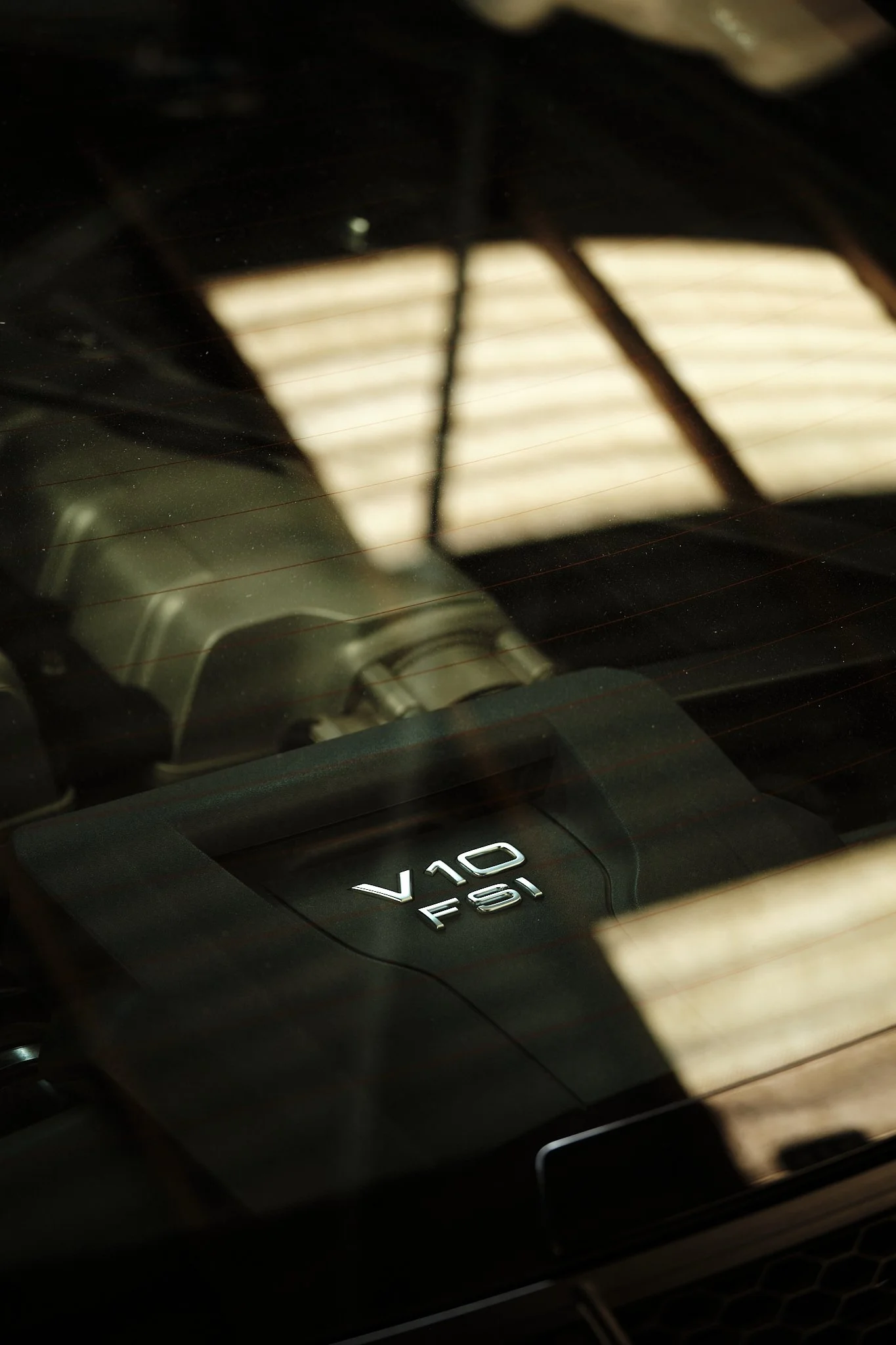 Close-up view of a car engine with a V10 FSI badge visible through the rear window.