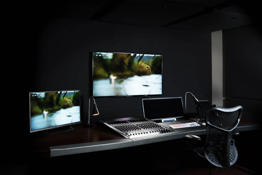 Control room with two monitors showing outdoor scenes, control panel, keyboard, mouse, and office chair.