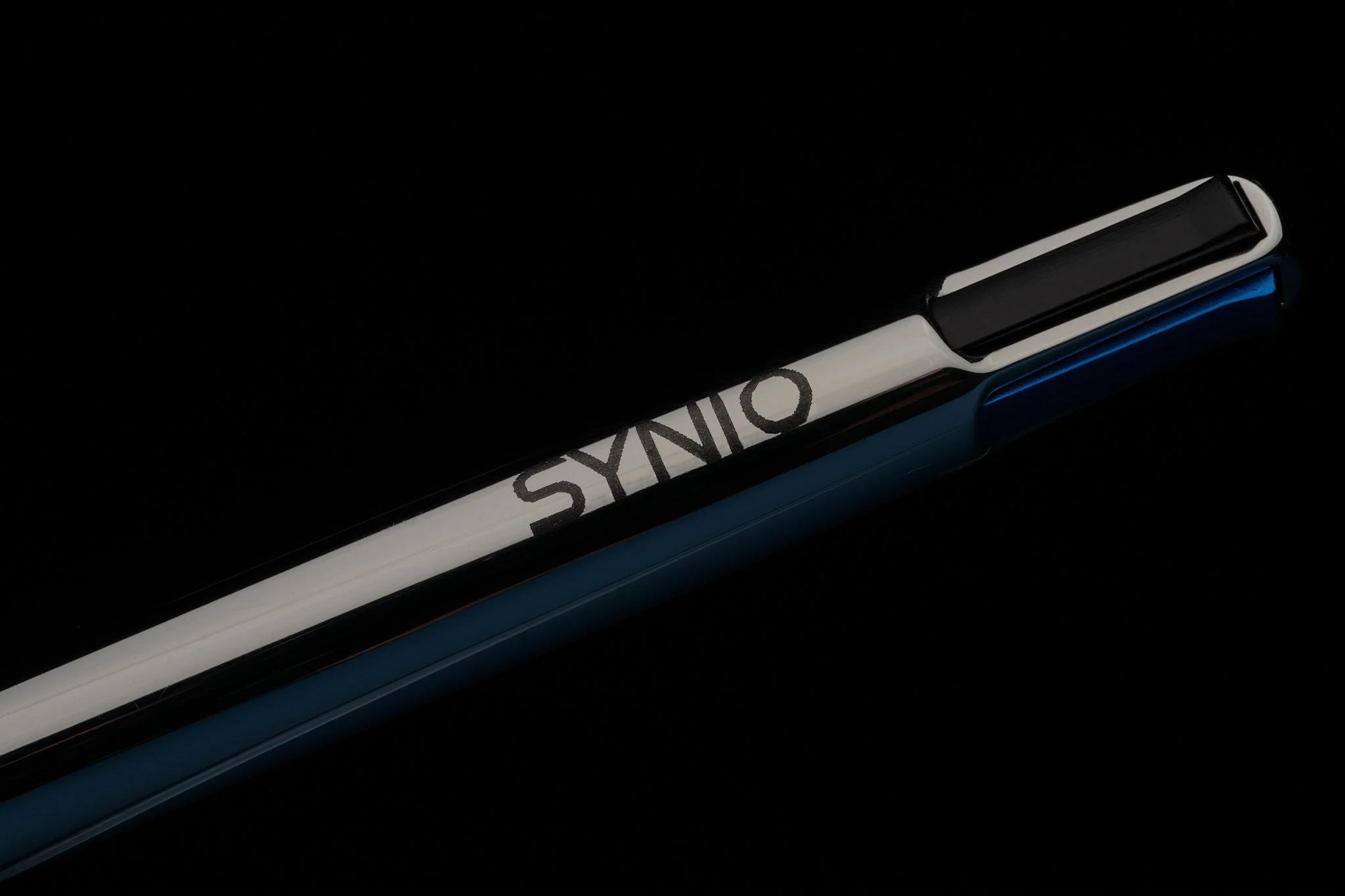 Close-up of a black, white, and blue pen with the word 'SYNO' printed on it, set against a black background.
