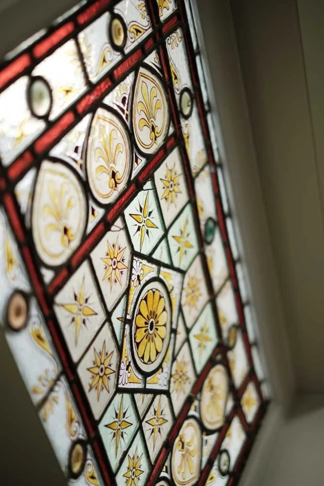 A stained glass window with intricate yellow, white, and red designs featuring floral and star patterns.