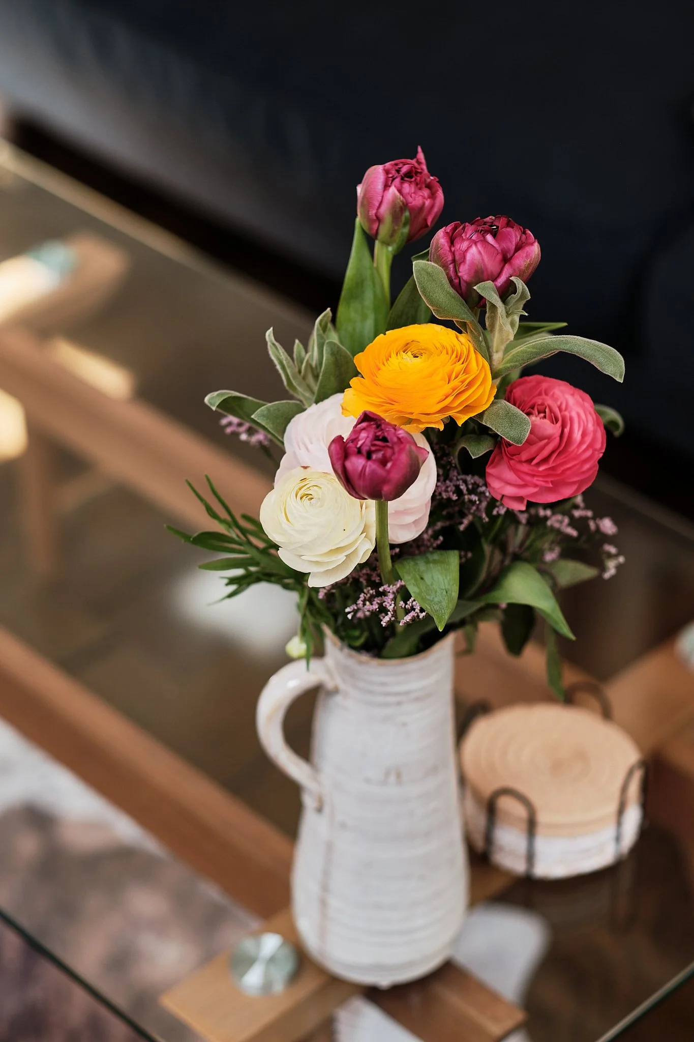 Colorful bouquet of flowers in a white vase on a wooden table.