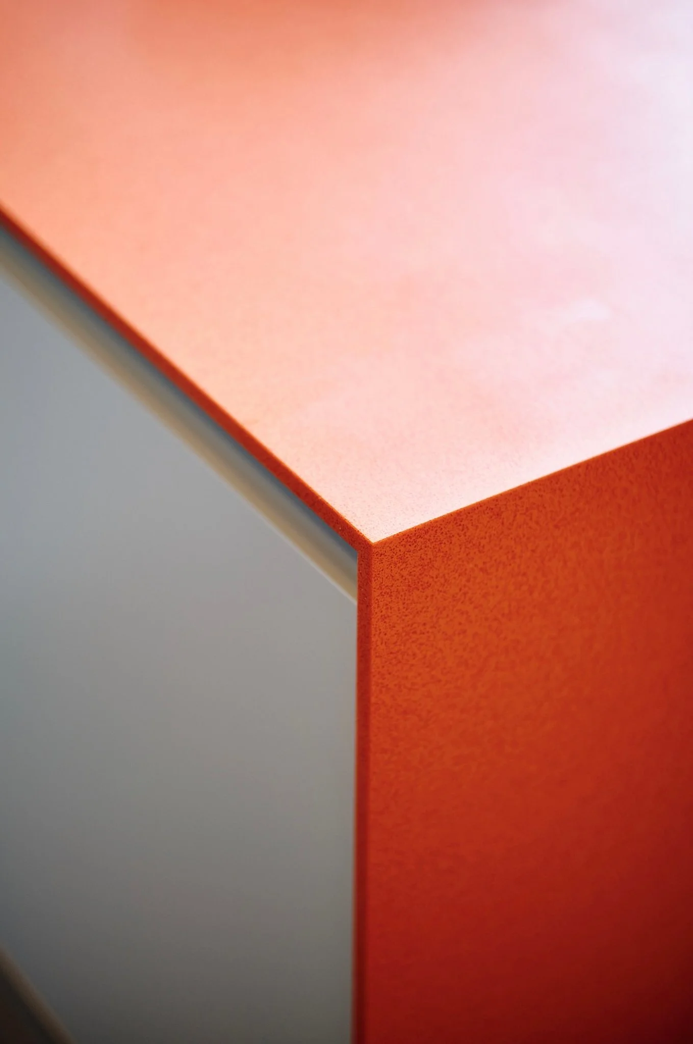 Close-up of a corner of a modern, minimalist desk with pastel pink and gray surfaces.