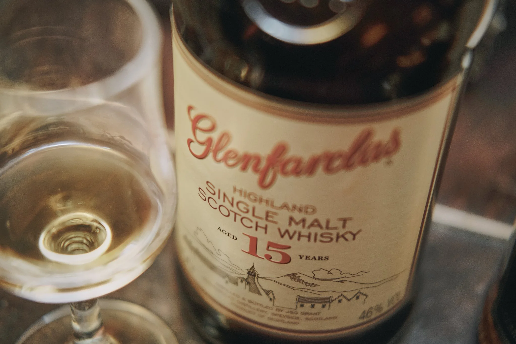 A bottle of Glenfarclas Highland Single Malt Scotch Whisky aged 15 years next to a glass of whisky.