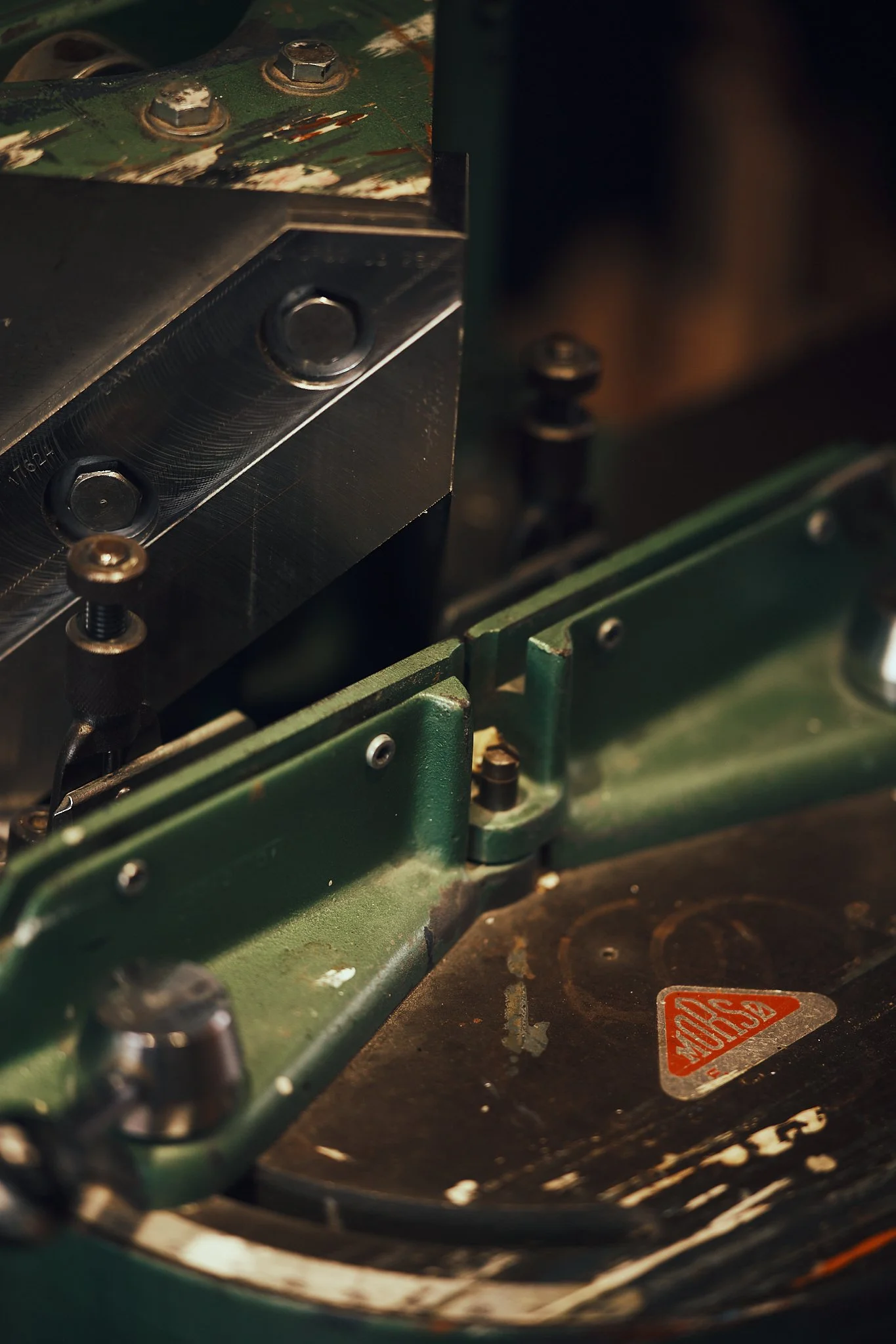 Close-up of a vintage typewriter with a green metal frame, showing the carriage and platen, with some rust and wear visible.