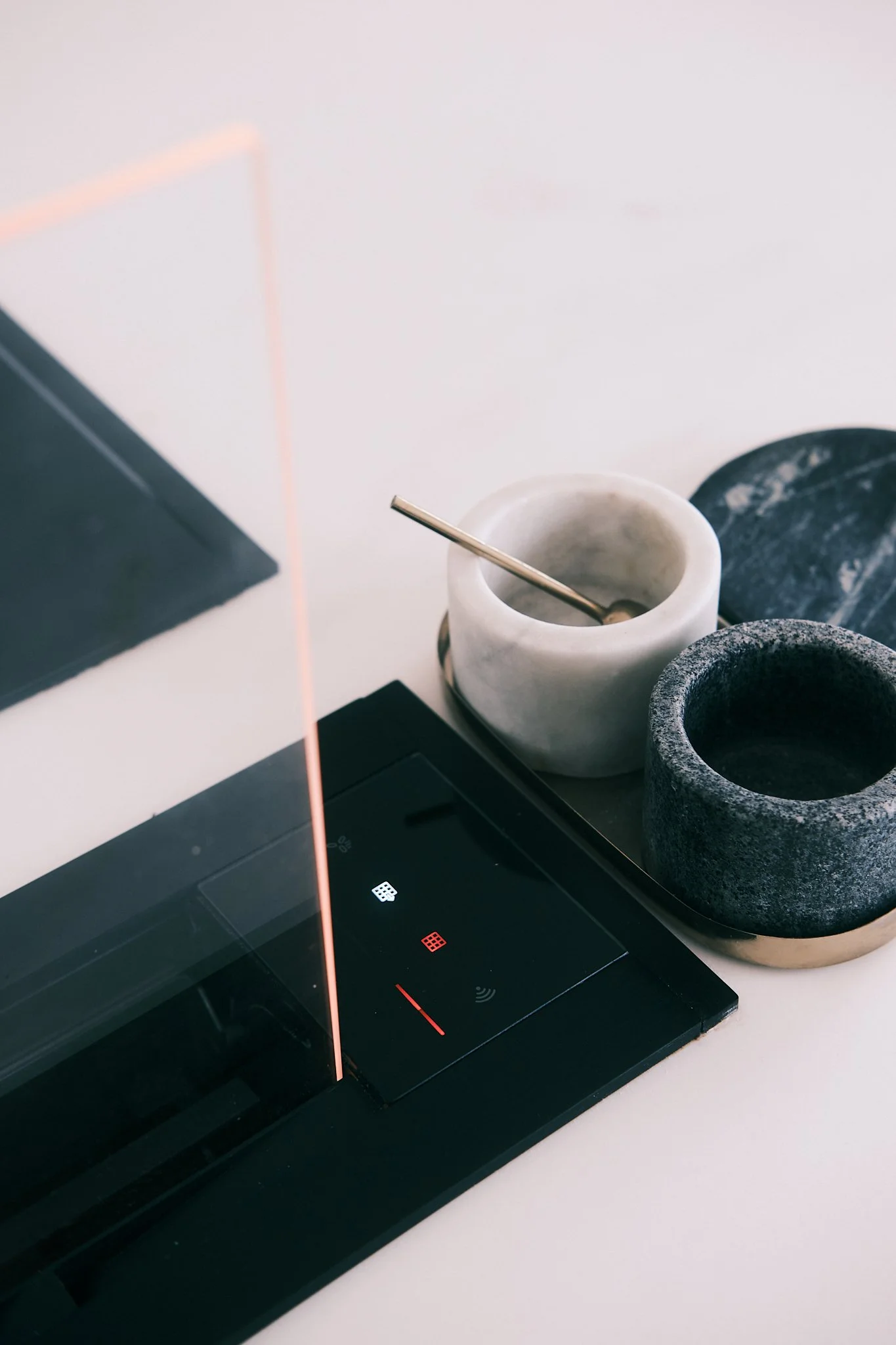 Coffee mug, stone mortar, and black tray on a white surface next to a closed laptop.