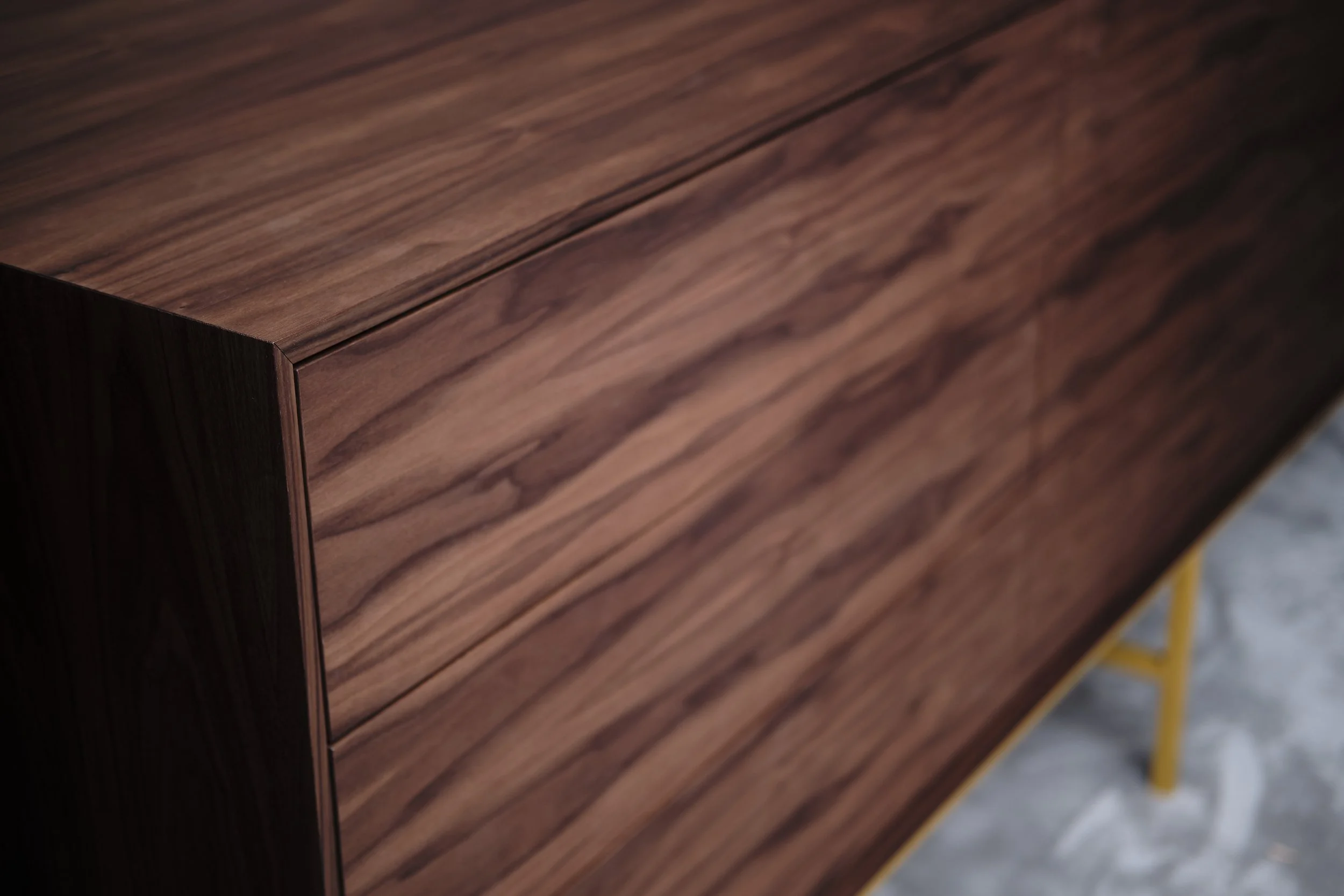 Close-up of a wooden cabinet or furniture piece with a dark, rich wood grain pattern.