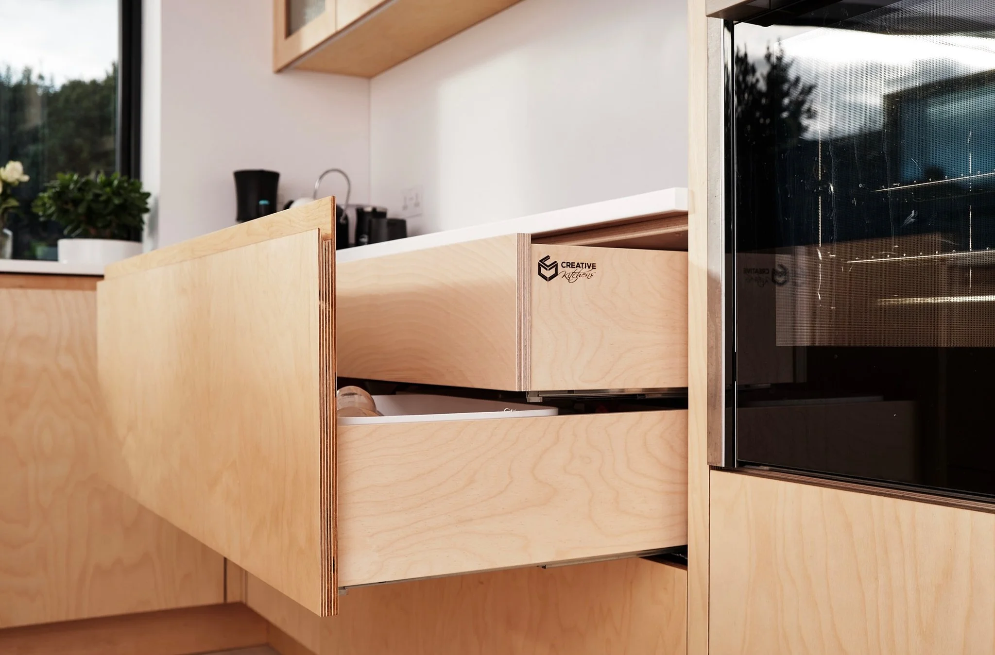 Open kitchen cabinet drawer with natural wood finish, labeled 'Creative cabinet'.