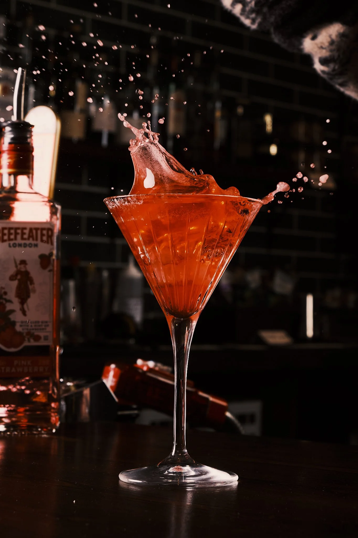 A cocktail glass with orange liquid splashing out.