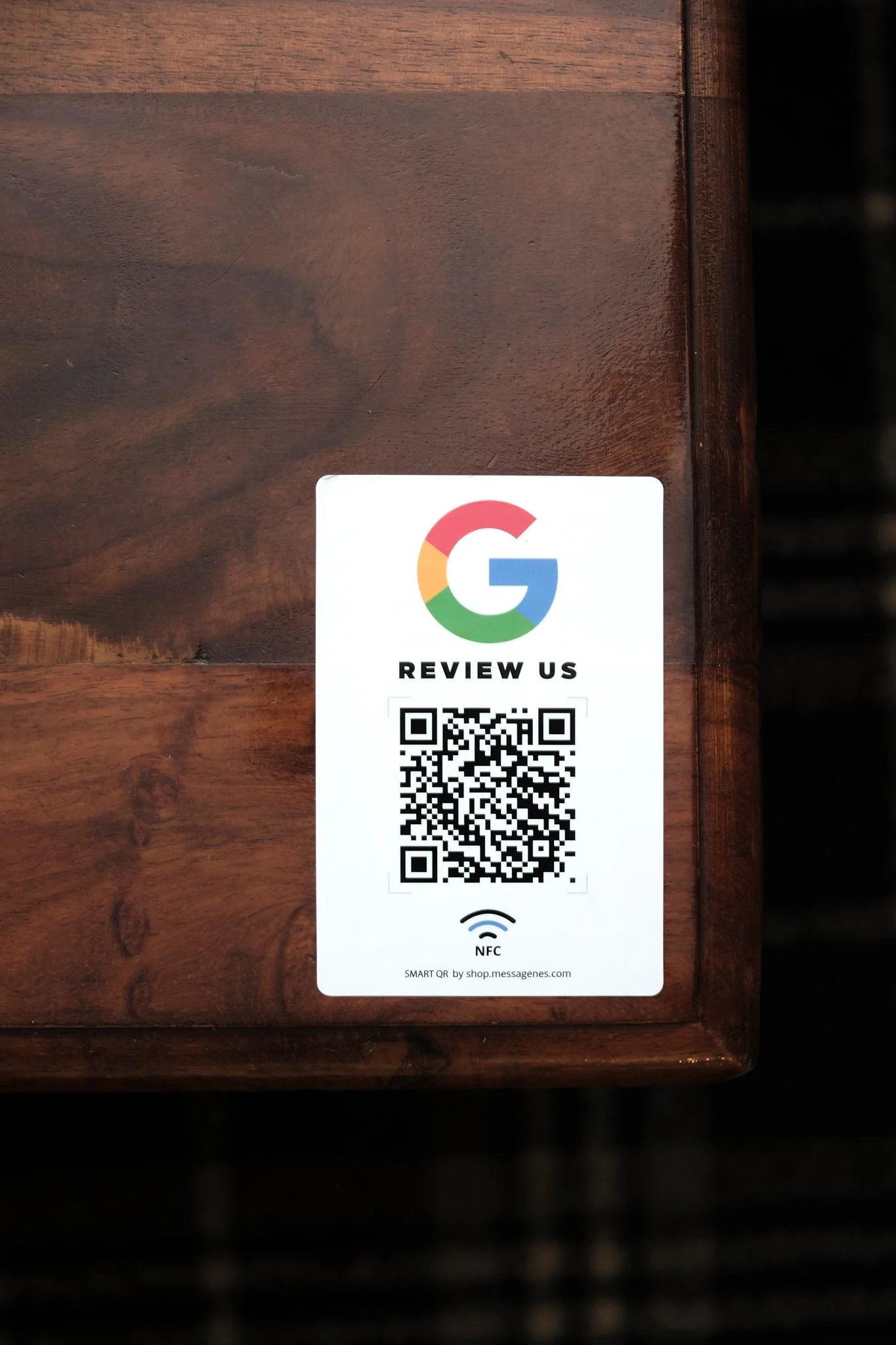 A sticker with a Google logo, a QR code for reviews, and the words 'Review Us' on a wooden surface.