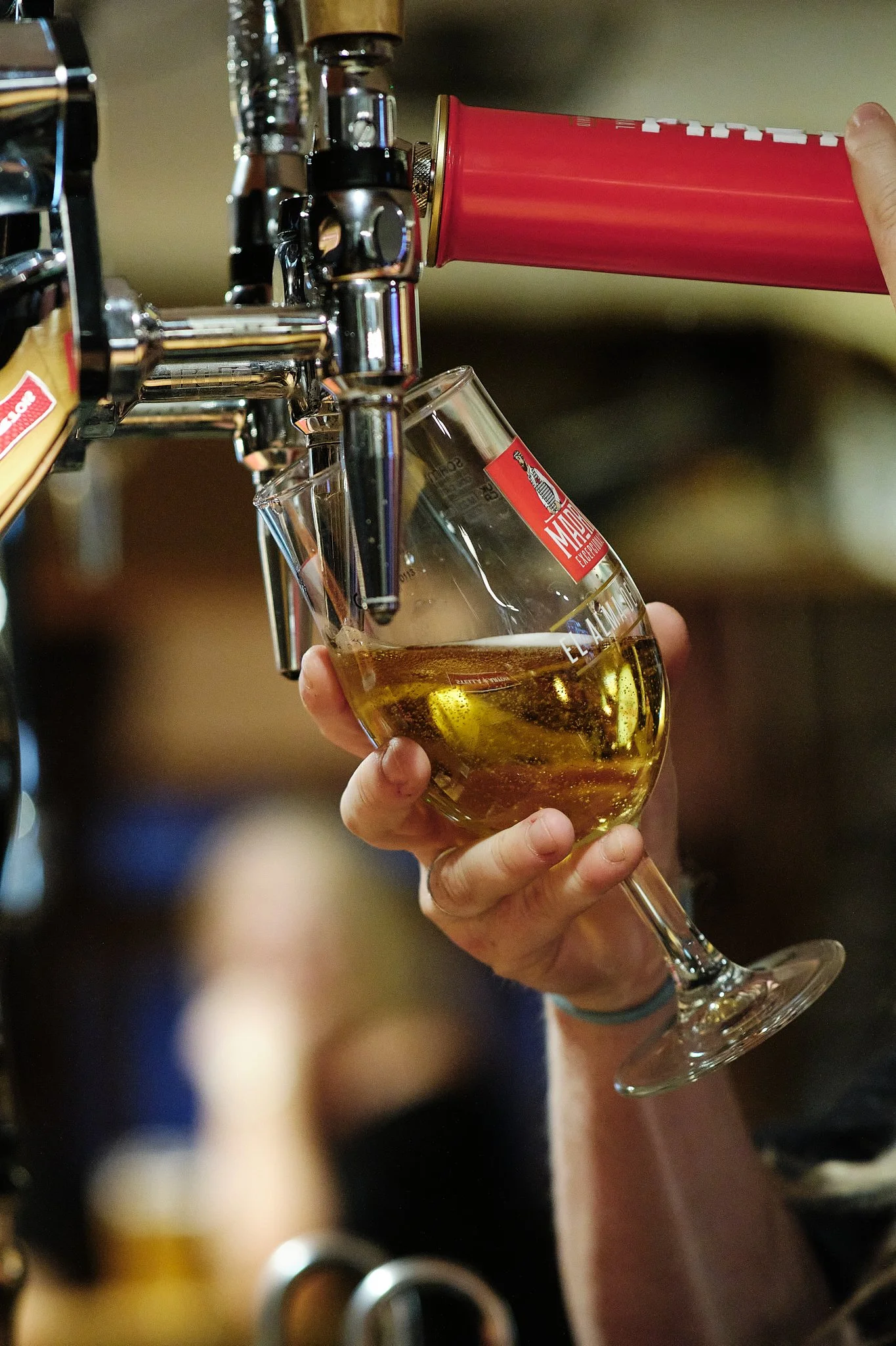 A person pouring a glass of beer from a draft tap.