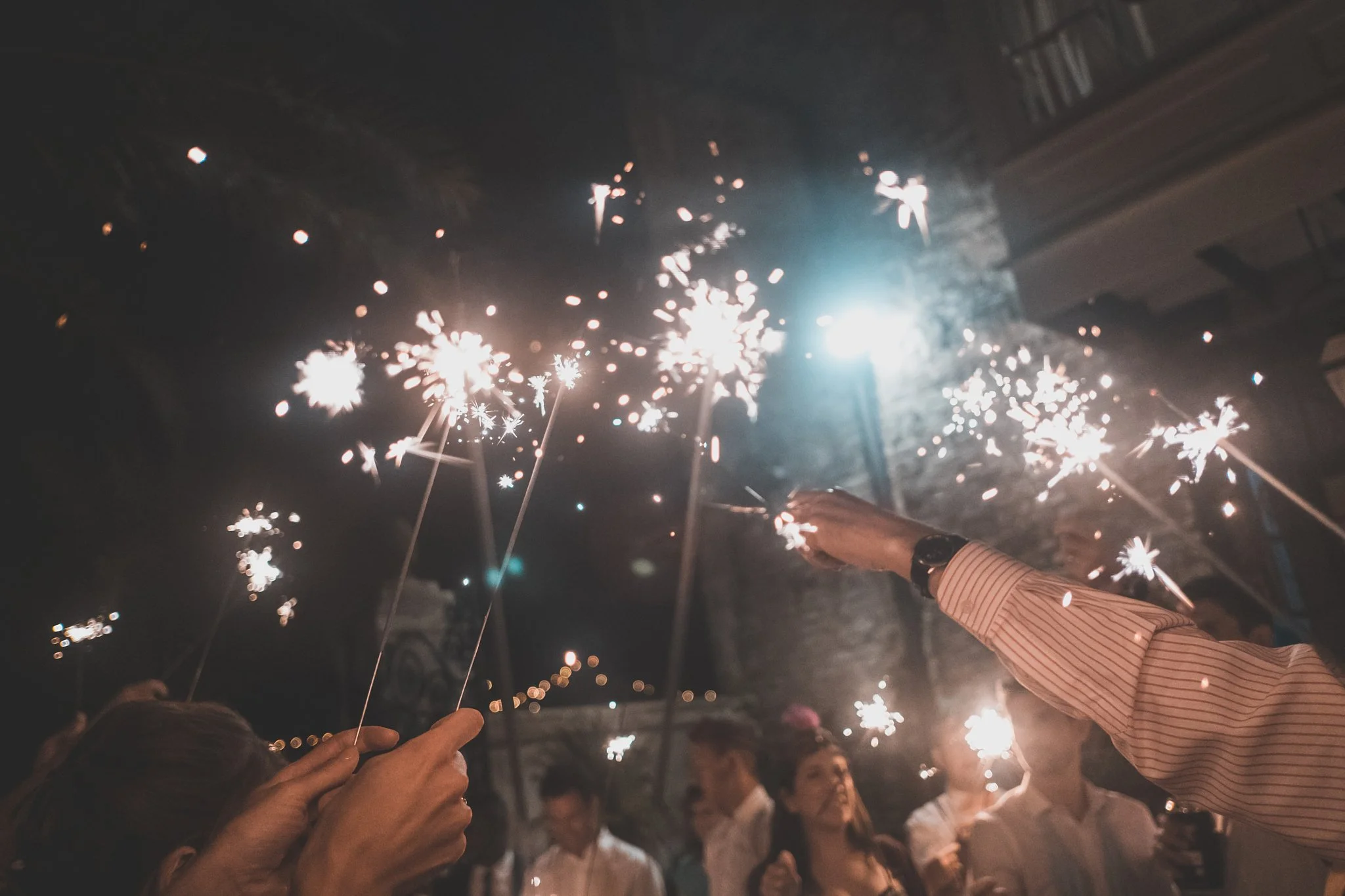 People holding sparklers during a celebration at night.