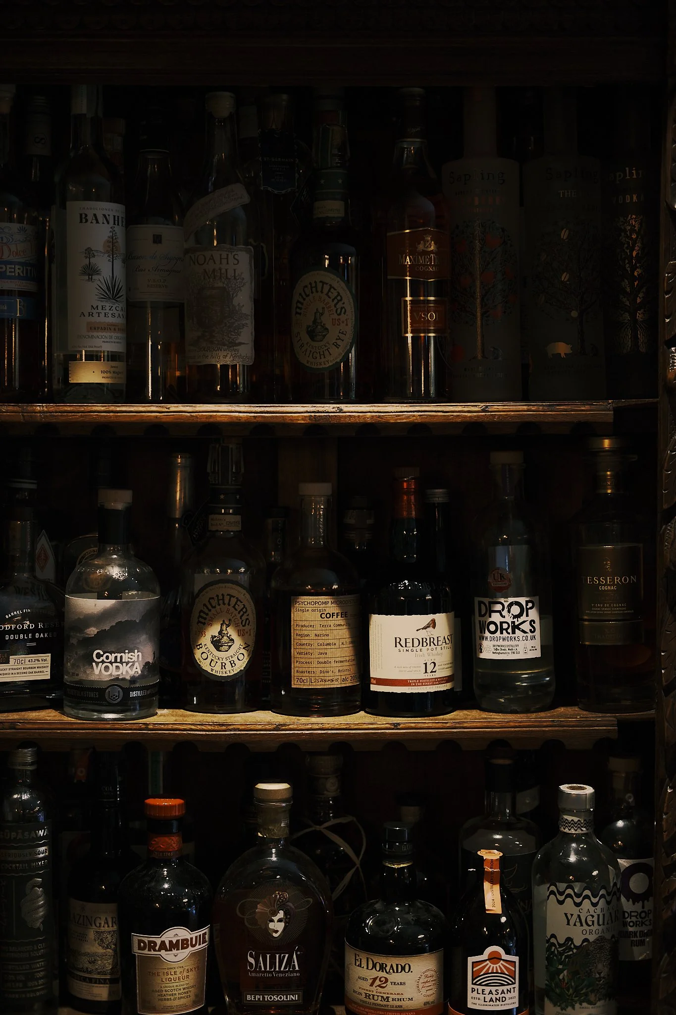 Shelf with assorted bottles of alcohol, including vodka, whiskey, rum, gin, and liqueurs. Hotel interior photography at THE PIG-in the Cotswolds