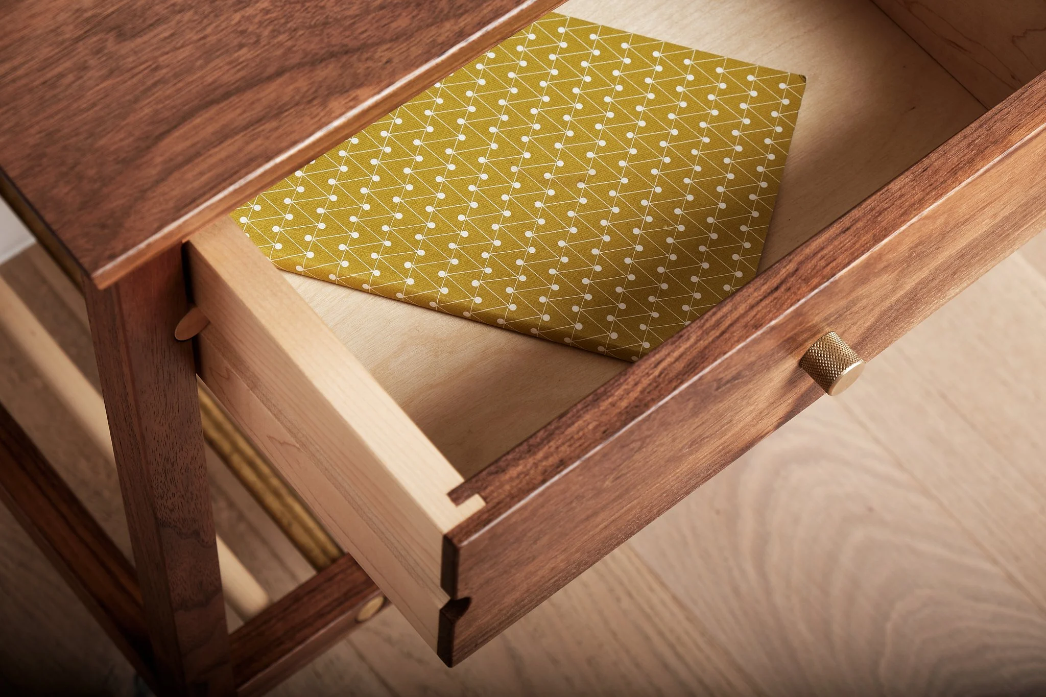 Open wooden drawer with a patterned yellow cloth inside.
