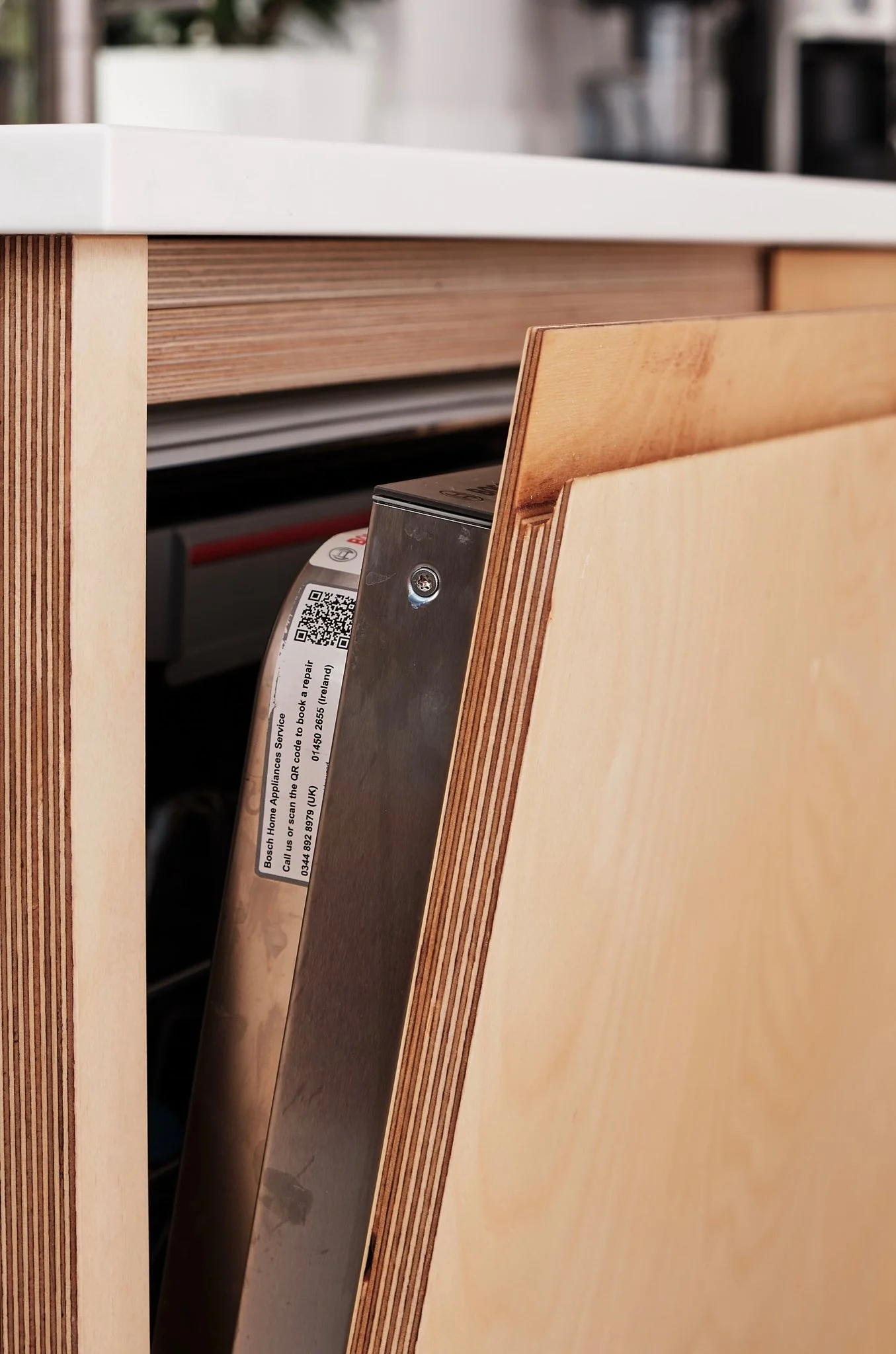 Close-up of the inside of a dishwasher, showing the metal rack and part of the wooden cabinetry surrounding it.