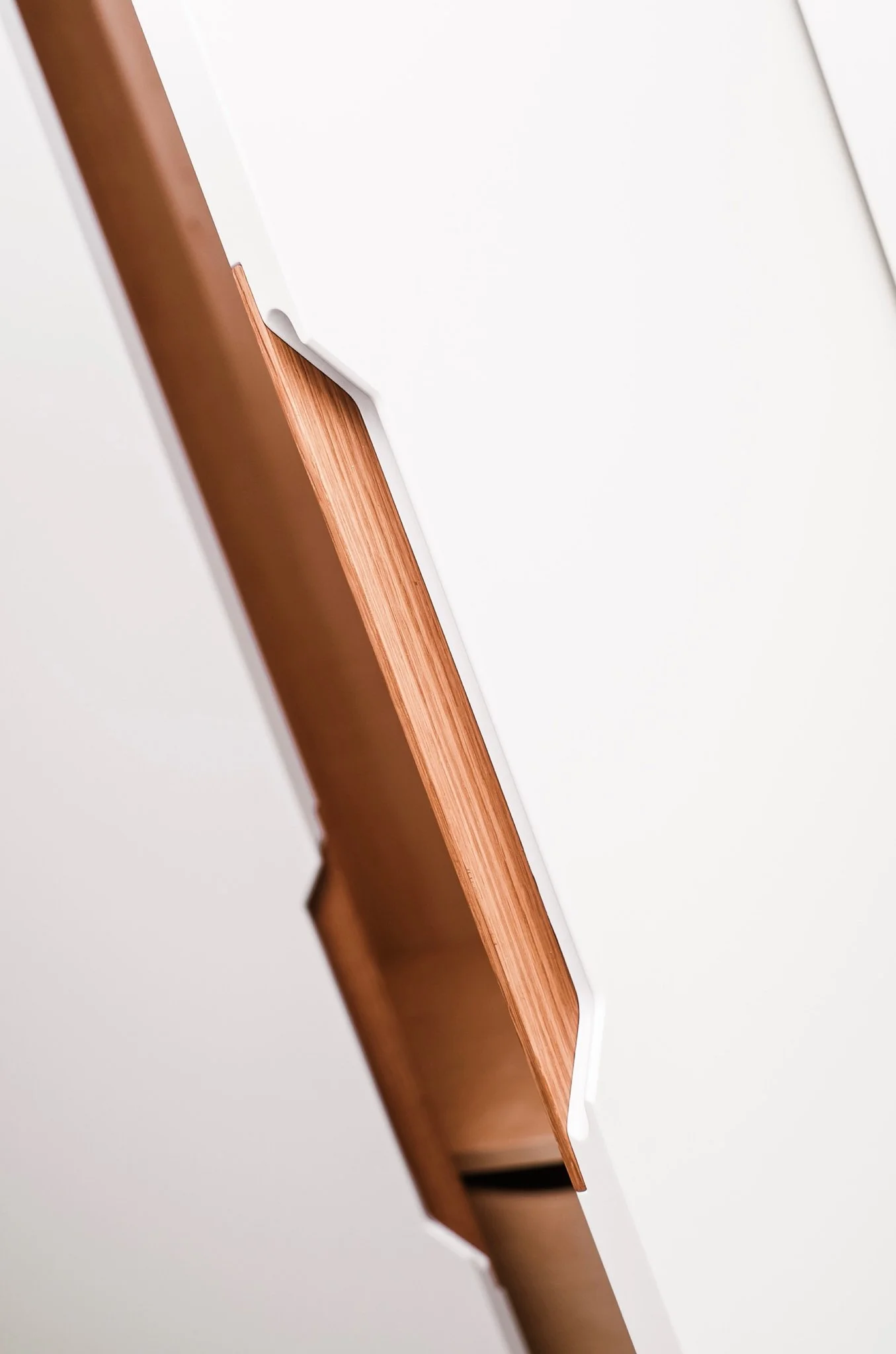 Close-up of a white cabinet with a wooden handle on a modern interior door.