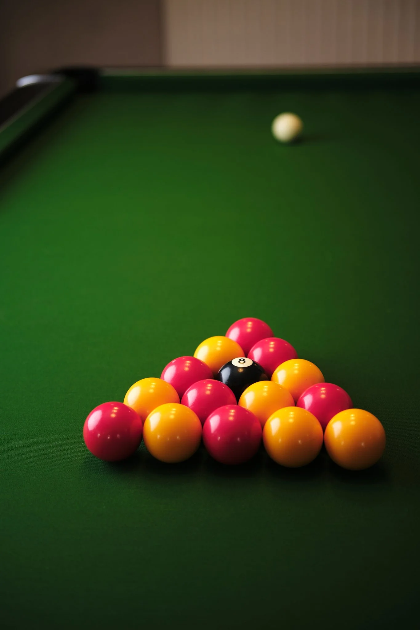 Pool table with a triangle of red, yellow, and black balls, and a white cue ball in the background.