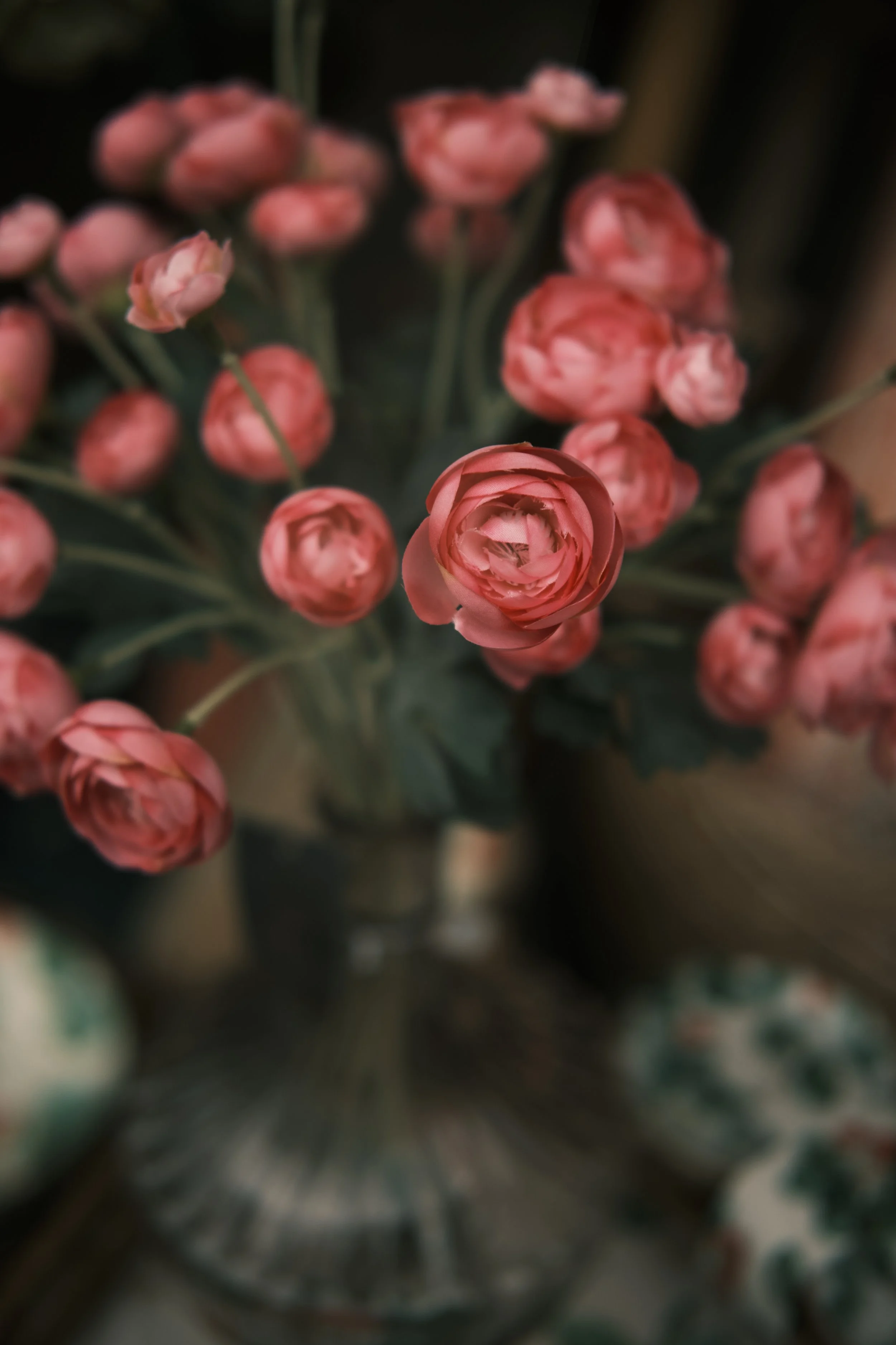 Close-up of a bouquet of pink ranunculus flowers in a vase, with one flower prominently in focus.