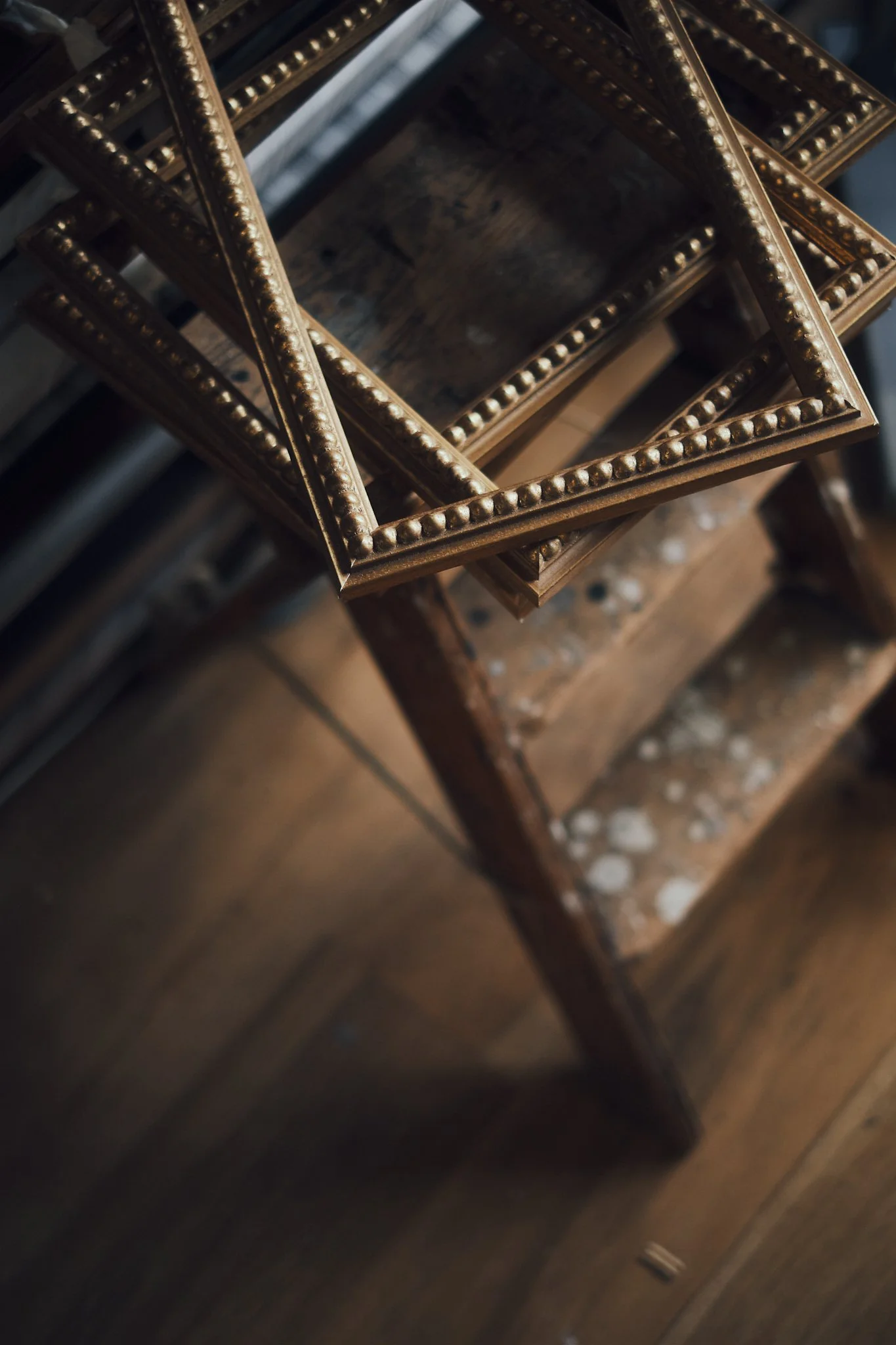 Stacked vintage picture frames with decorative beaded edges on a worn wooden table.