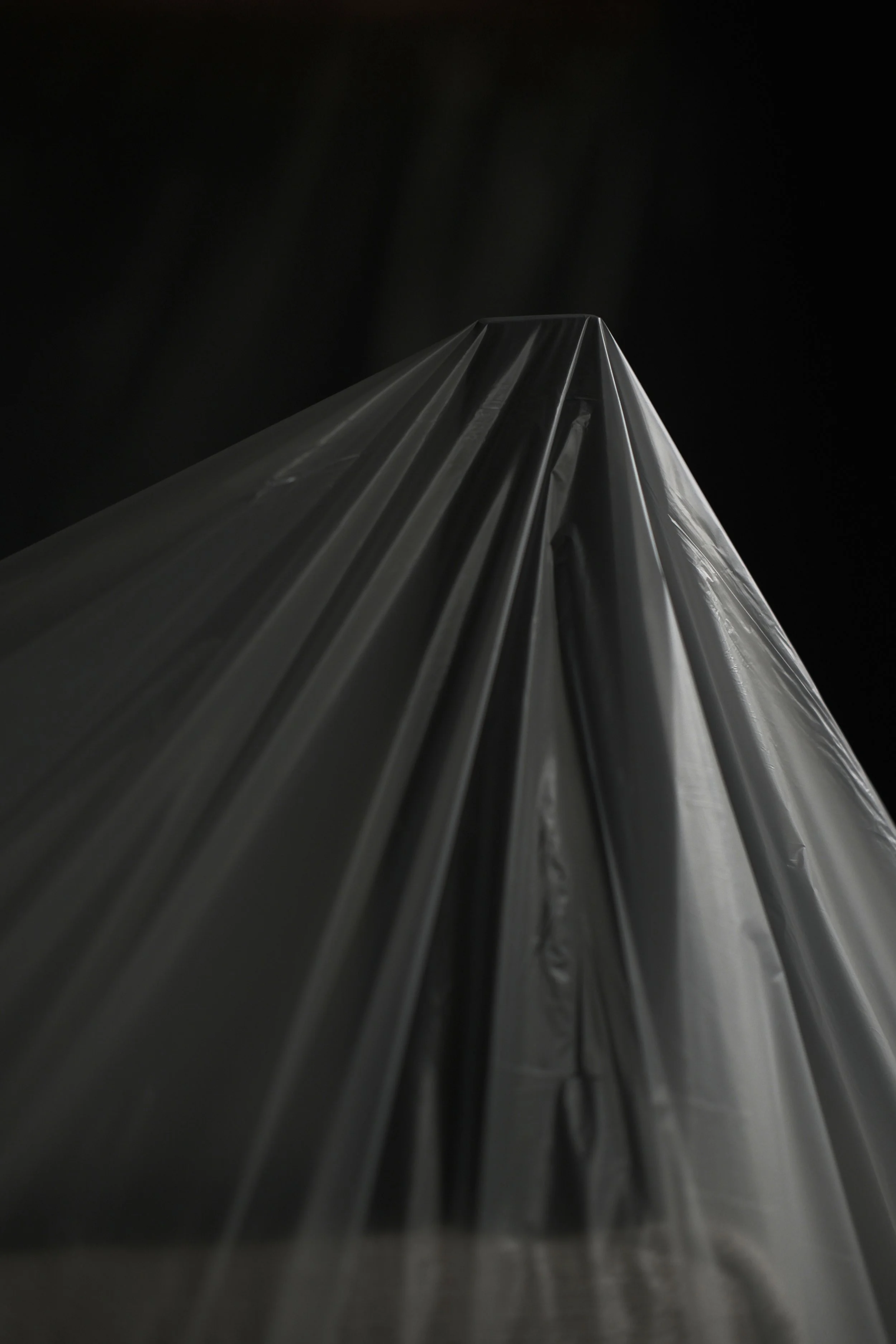 Close-up view of a reflective metallic or plastic sheet with a dark background, taken from a low angle.