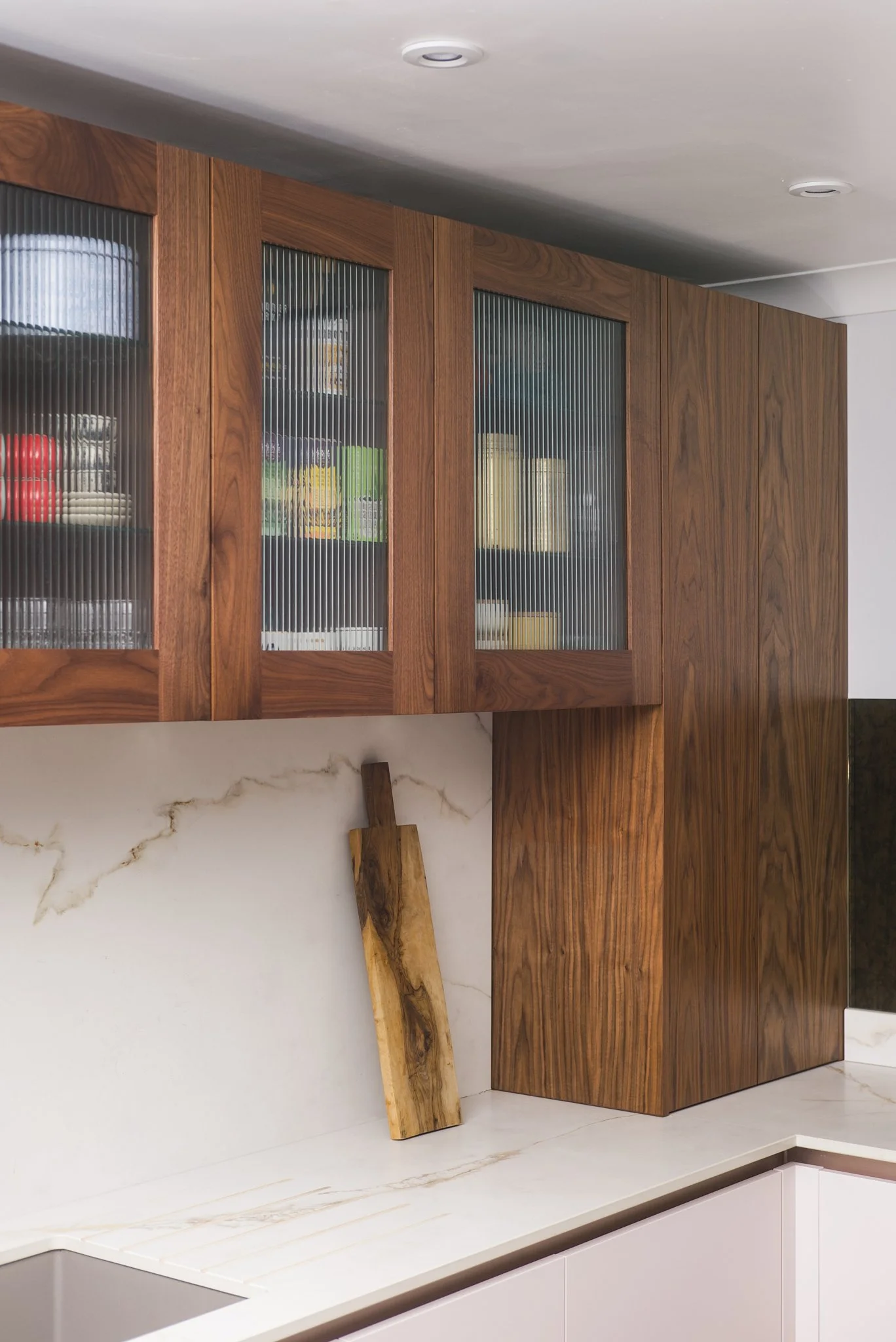Modern kitchen with wooden cabinets and marble countertop, with a piece of wood leaning against the wall.