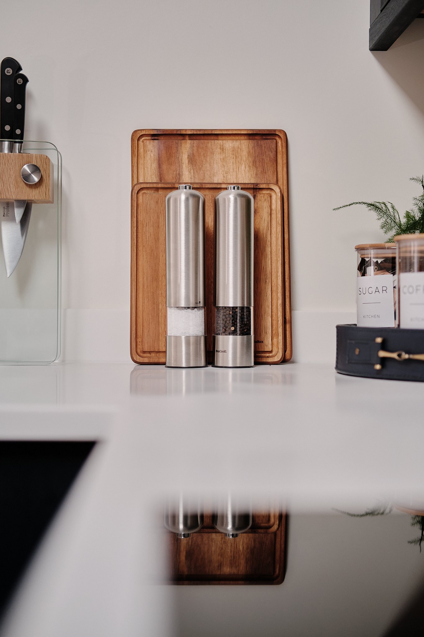 Salt and pepper shakers on a wooden tray in a modern kitchen.
