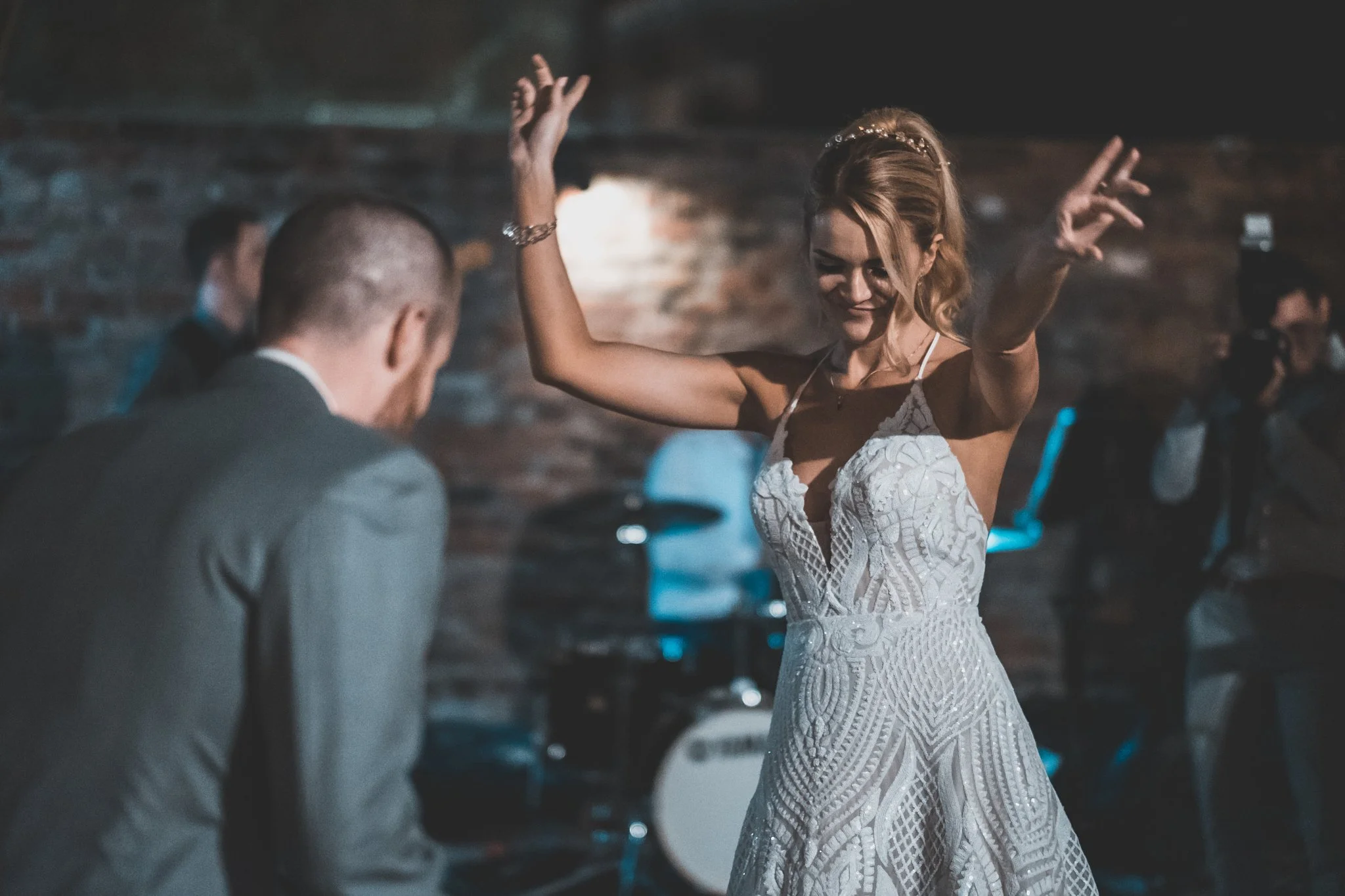A woman in a white dress dancing with a man dressed in a suit, in a dimly lit setting.