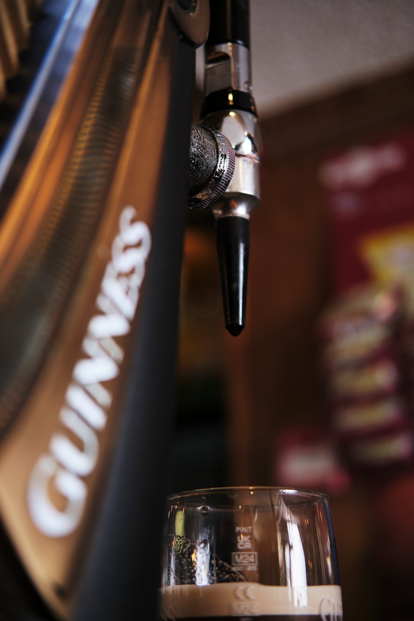 Close-up view of a Guinness draft beer tap pouring dark beer into a glass.