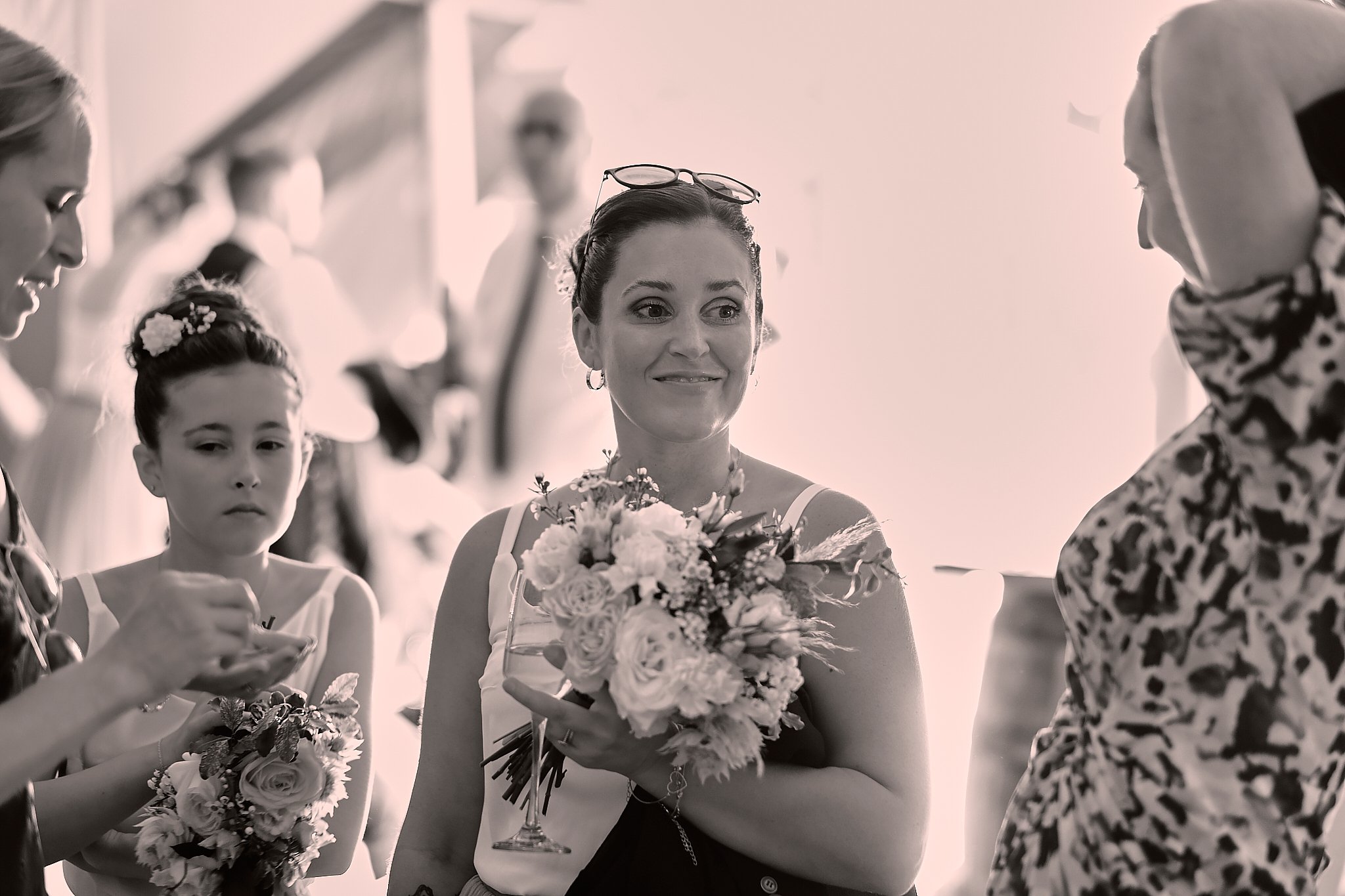 A woman holding a bouquet of flowers, surrounded by young girls, at what appears to be a celebration or ceremony