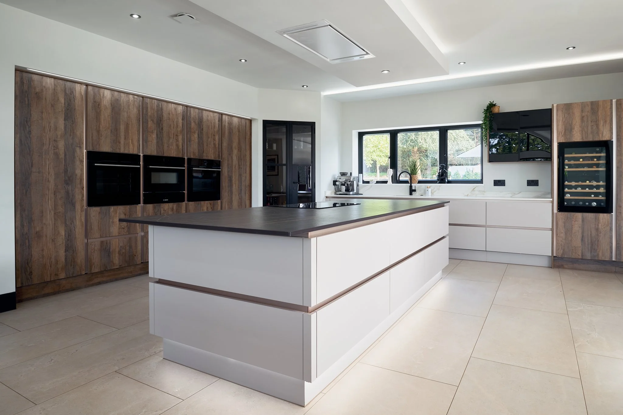 Modern kitchen with white cabinets, a black countertop island, wooden cabinetry, a wine cooler, and a large window