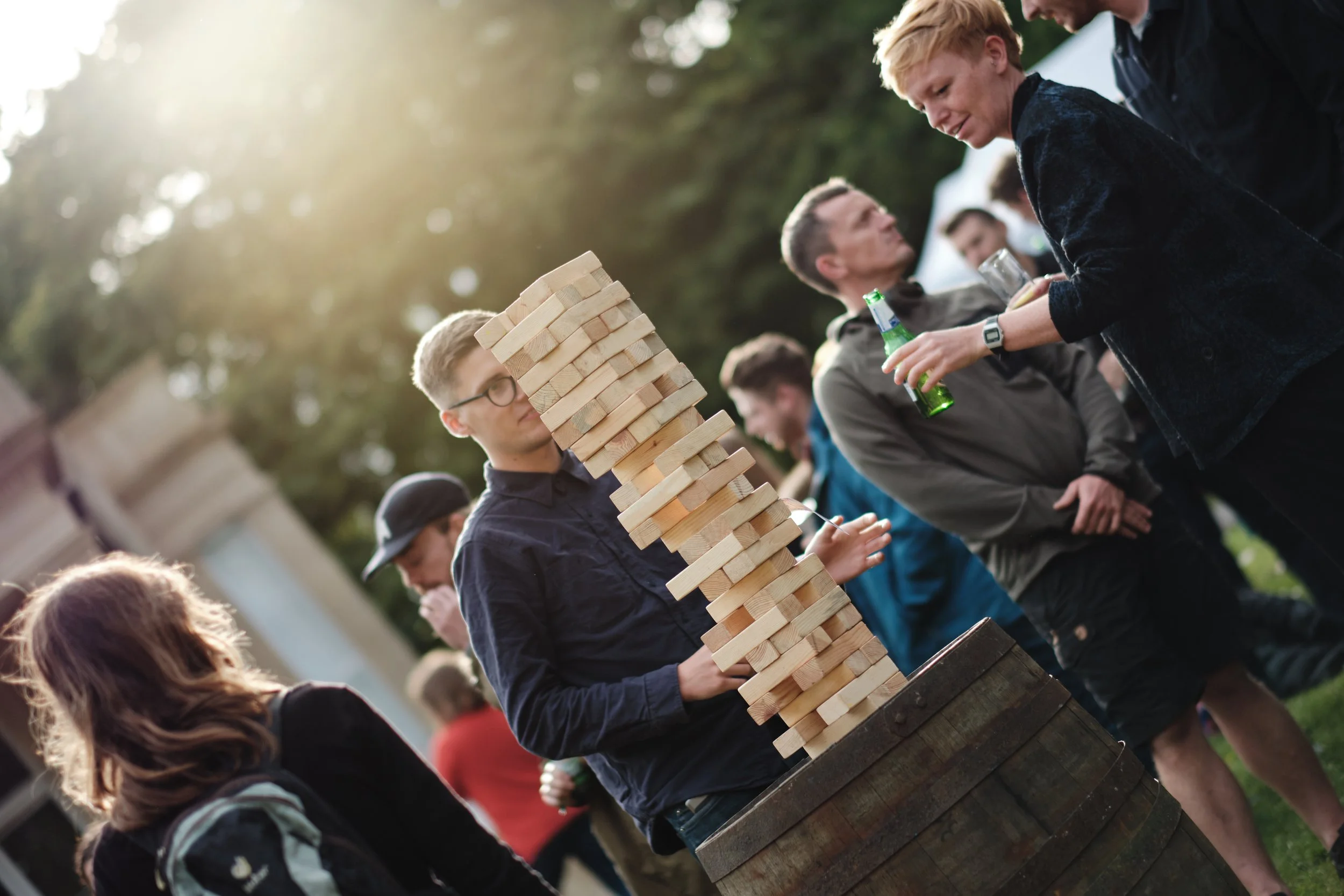 People playing giant Jenga outdoors during a social gathering.