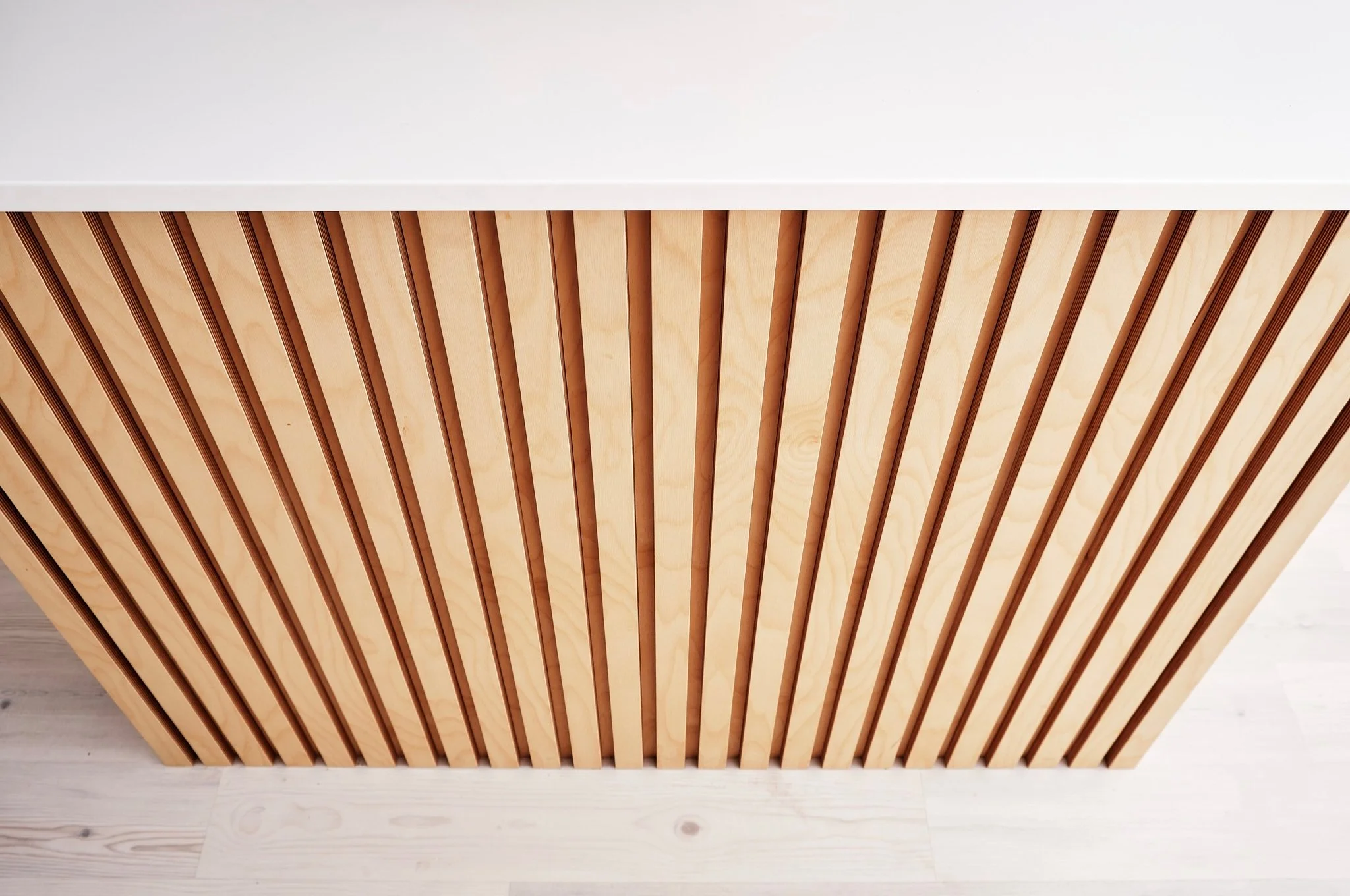 Close-up of a wooden slatted cabinet door with a white countertop on top.