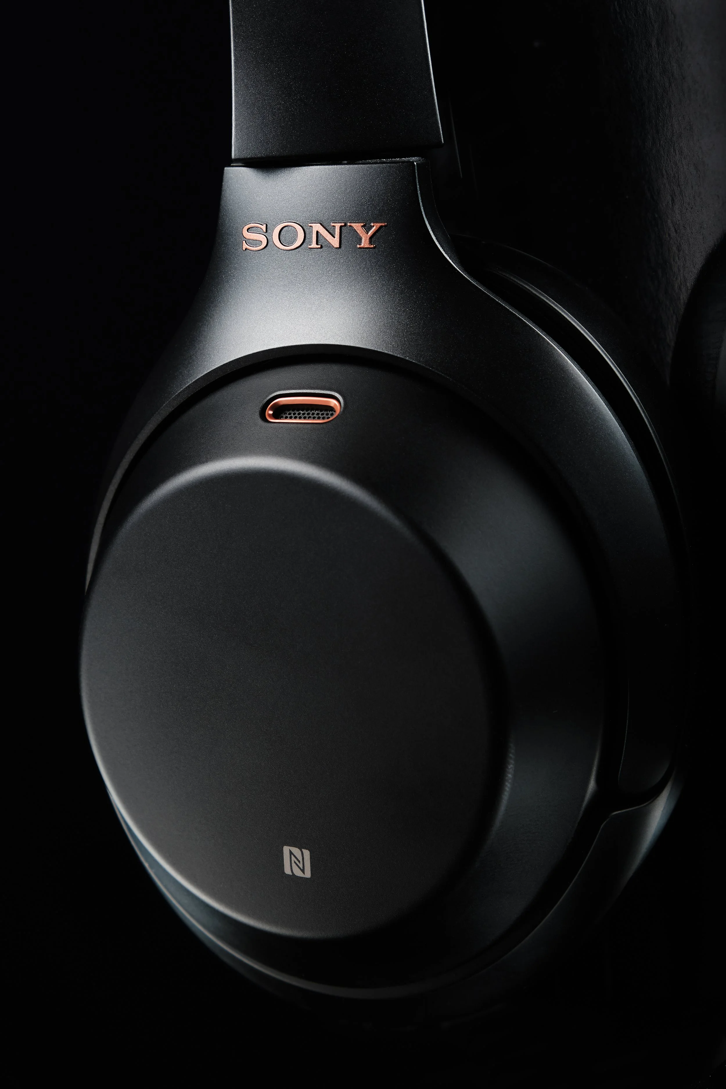 Close-up of a black Sony headphones with a copper-colored Sony logo.