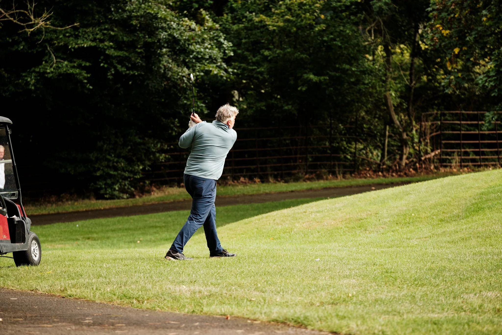 A man playing golf on a golf course, swinging his club.