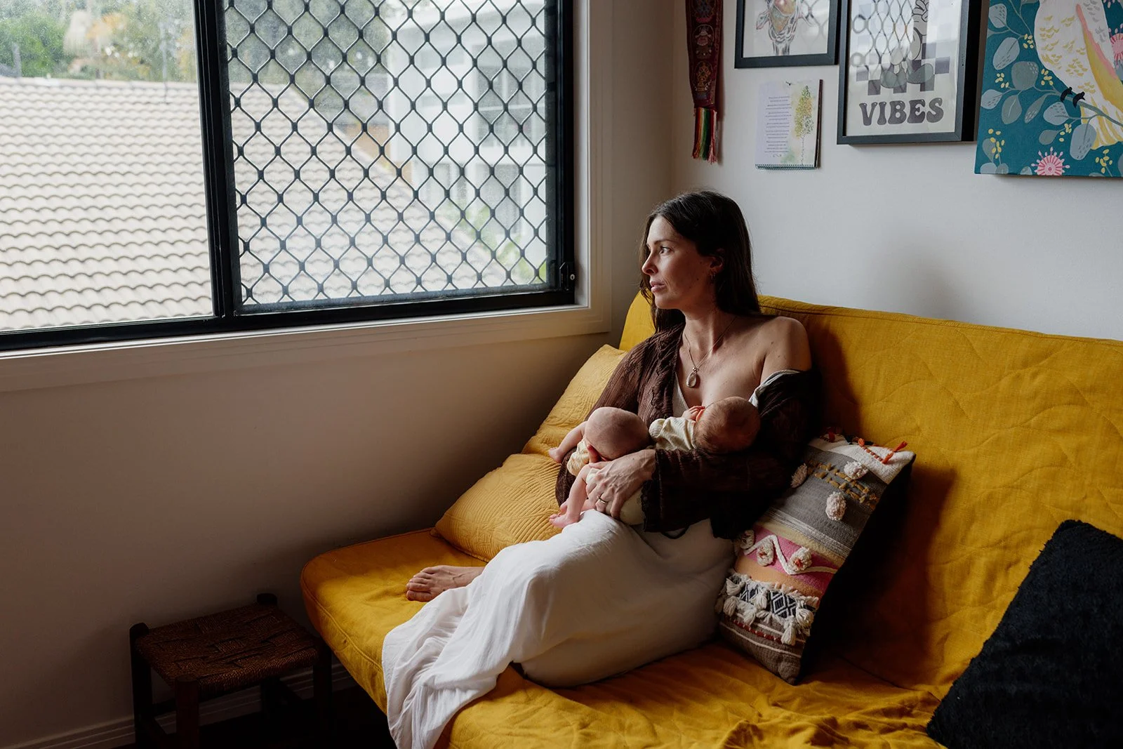 Gold Coast newborn photographer captures mother at home holding tiny twin babies during Gold Coast newborn photo shoot.