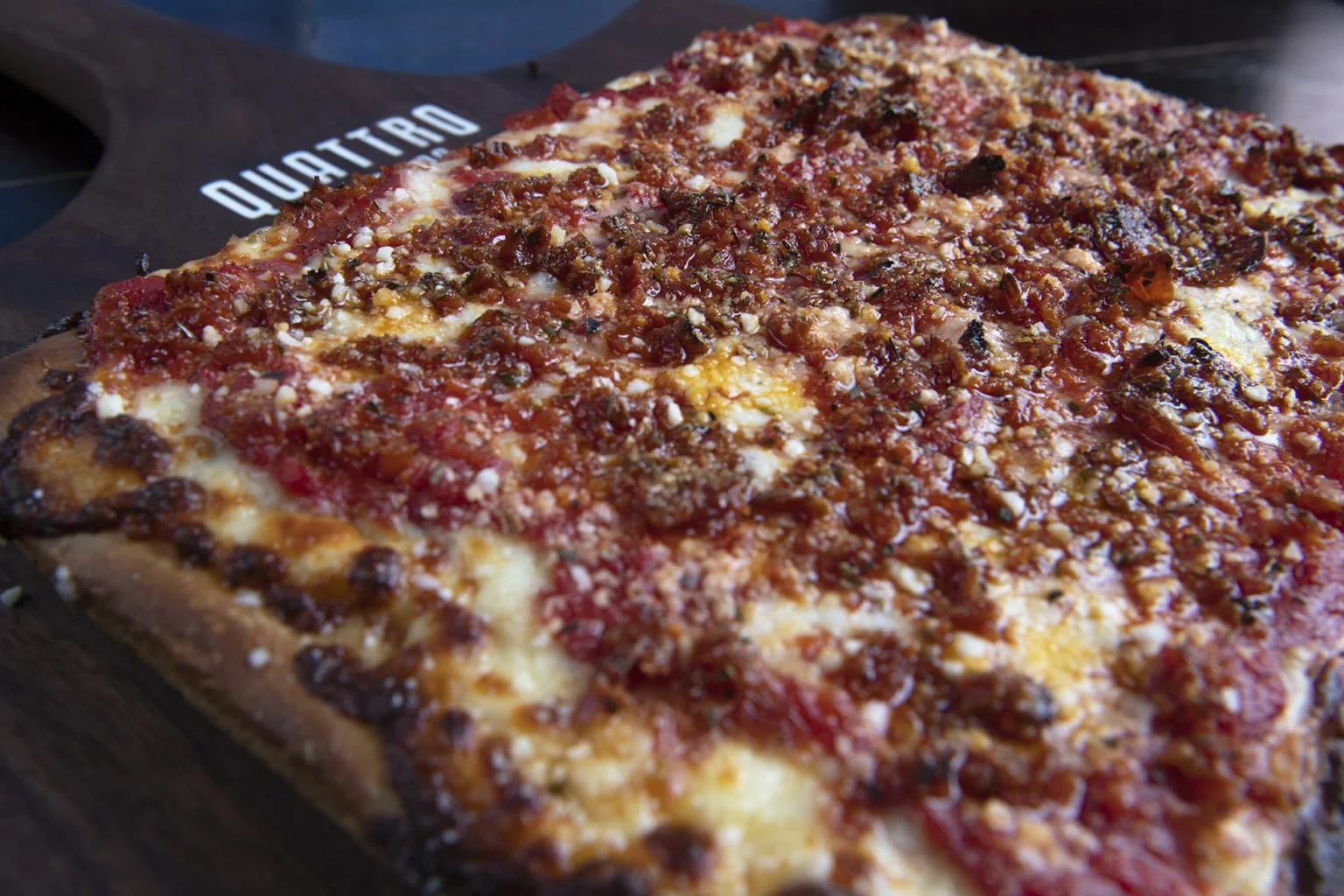 Close-up of a rectangular pepperoni pizza with cheese and tomato sauce on a wooden pizza board.