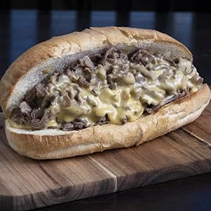 Philly cheesesteak sandwich with beef, melted cheese, and sautéed onions in a hoagie bun