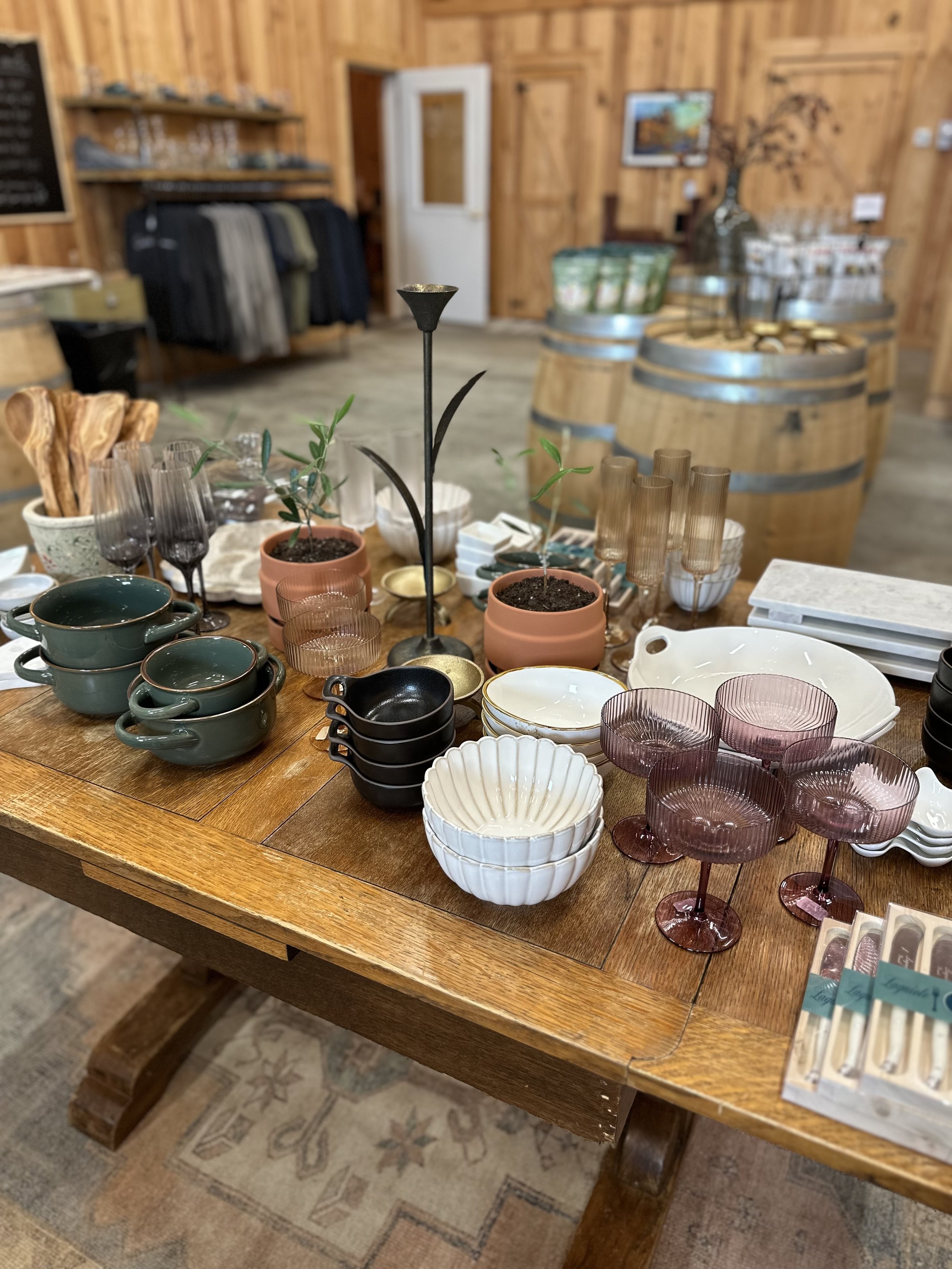 Display of various glassware, bowls, and cups on a wooden table inside a rustic store.
