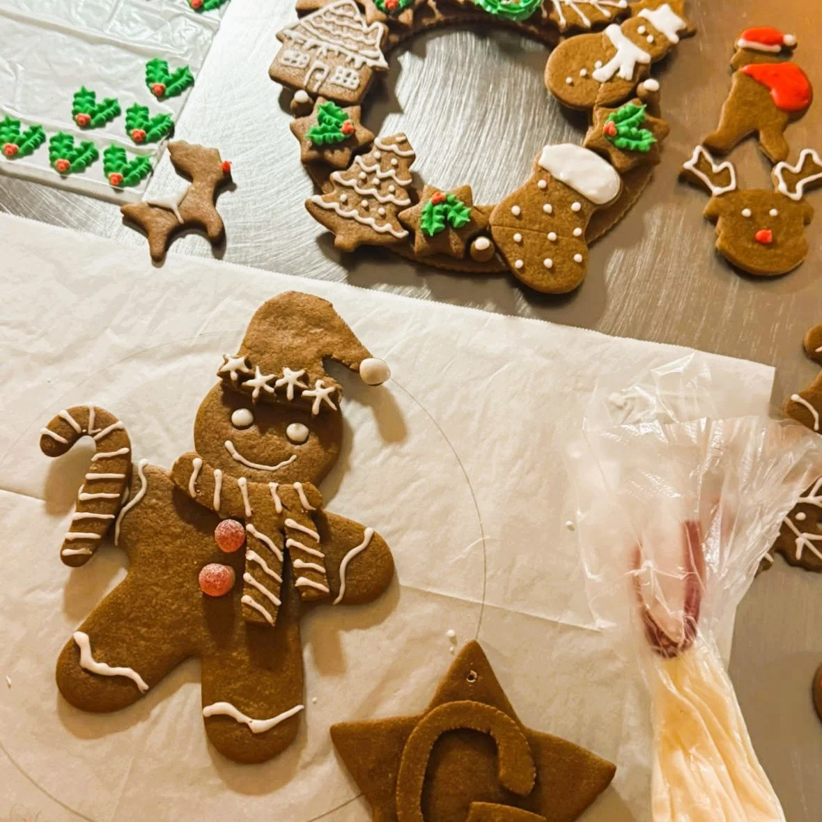 Iced gingerbread man in a Santa hat beside a gingerbread wreath, decorated at a Cookie Queen workshop in Truro.jpeg