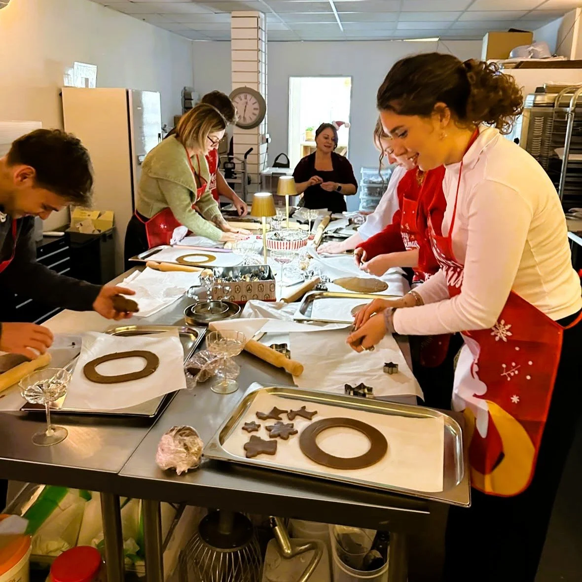 Guests in Christmas aprons rolling and cutting gingerbread dough at a Cookie Queen baking workshop in Truro.jpeg