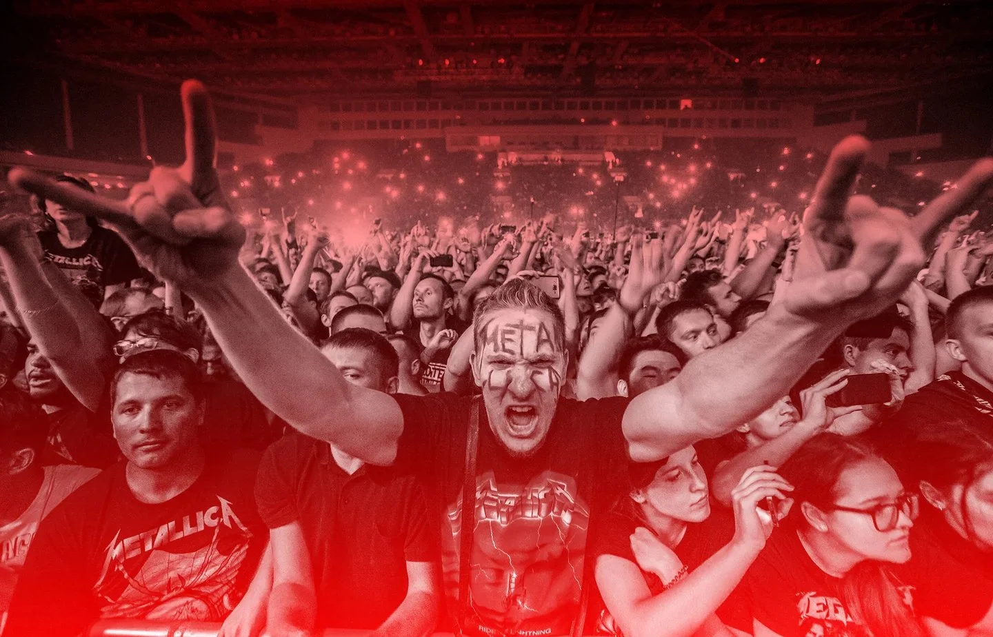 a crowd of humans enjoying a concert, with one having the word "metal" written on their face