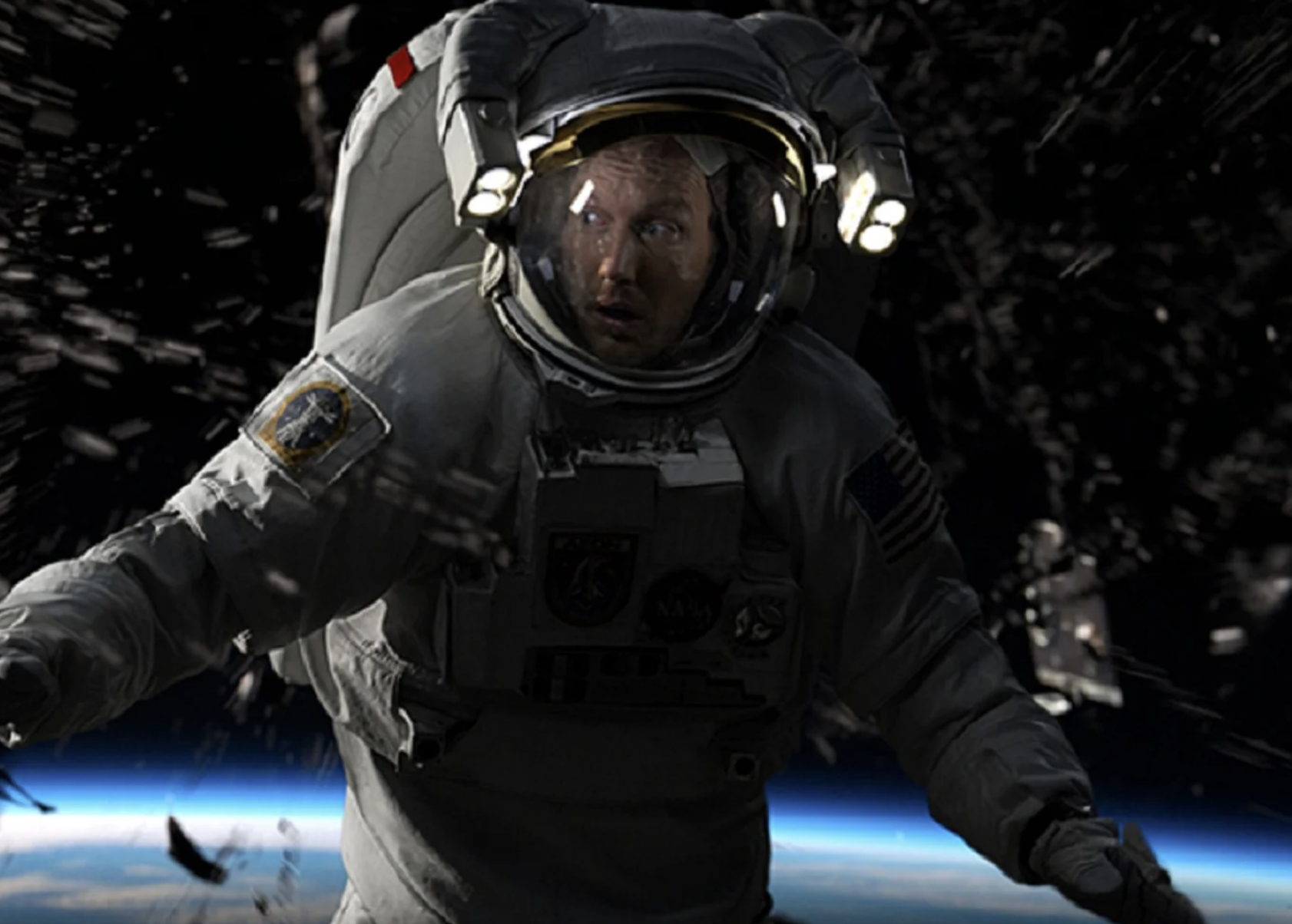 A human wearing a spacesuit looks to the left with a shocked and anxious expression