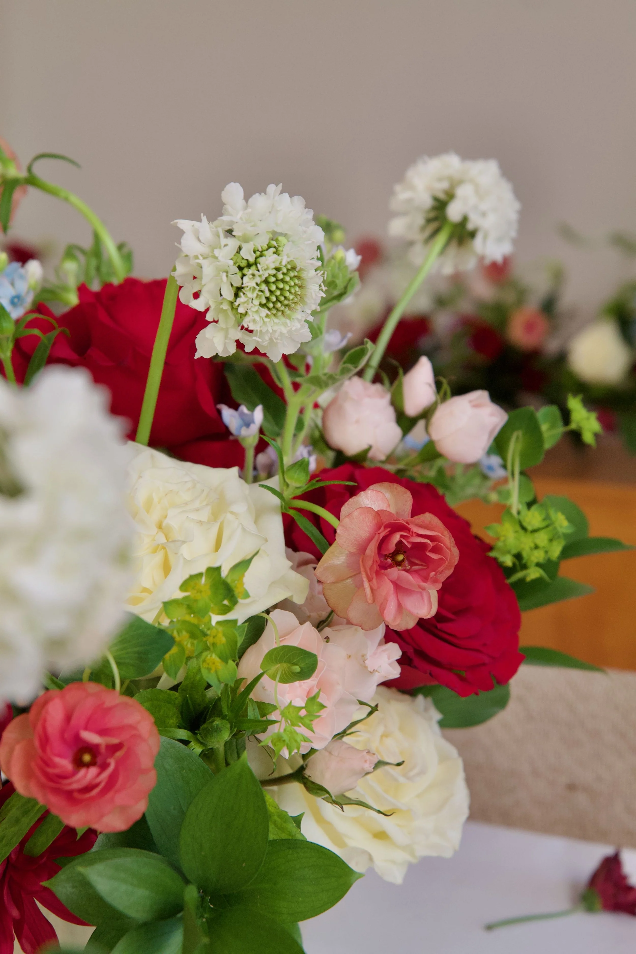 Close-up of a colorful flower bouquet featuring white, red, and pink flowers with green leaves.