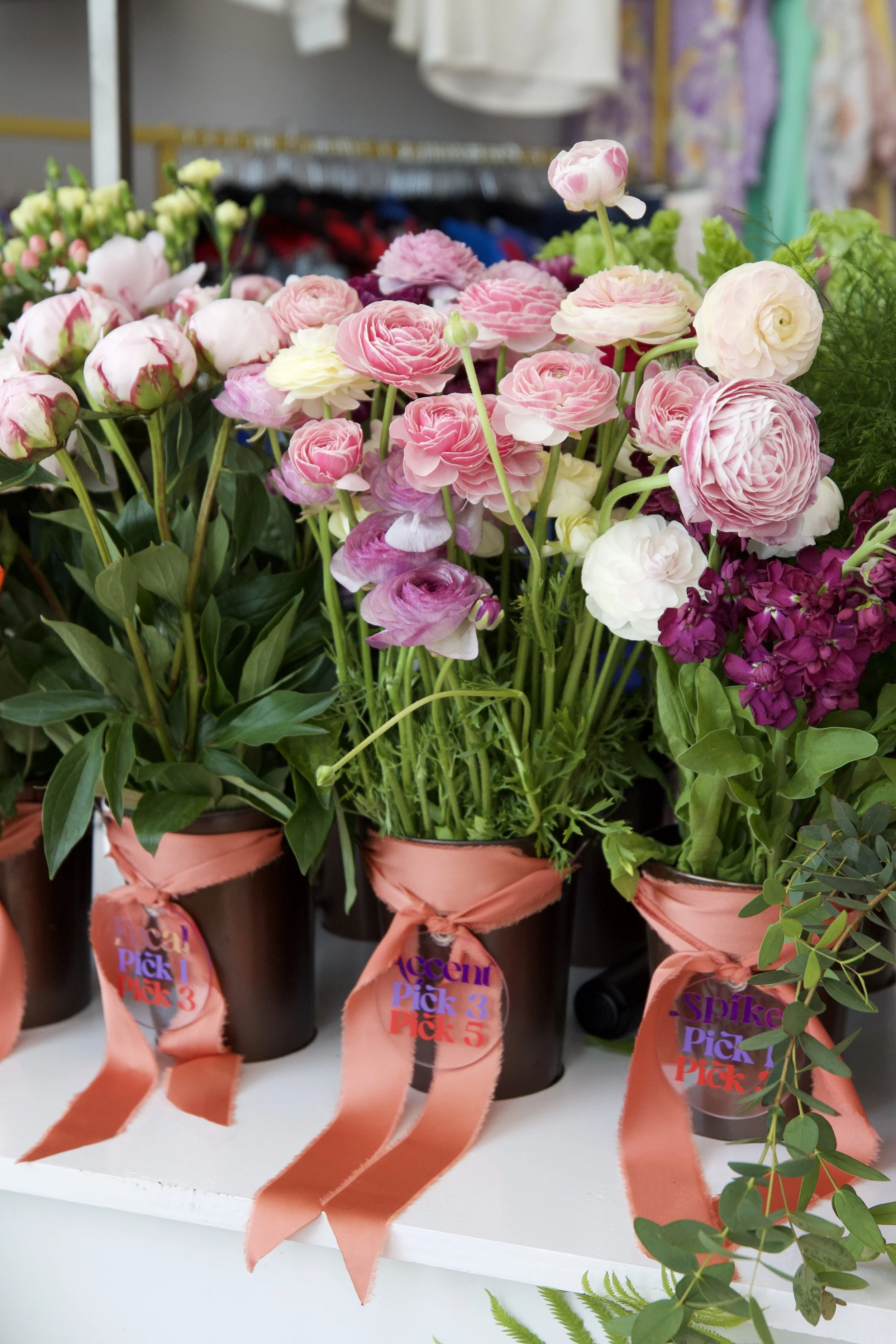 Vases of pink, white, and purple flowers with ribbons and labels on display at a wedding in metro detroit.