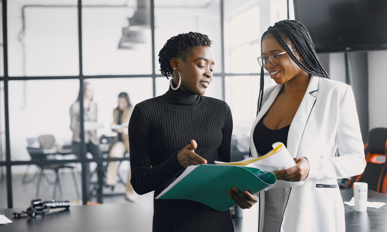 two women in professional workwear looking at reports