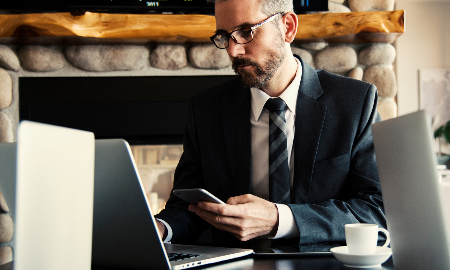 man sitting with a laptop in front of stone fireplace
