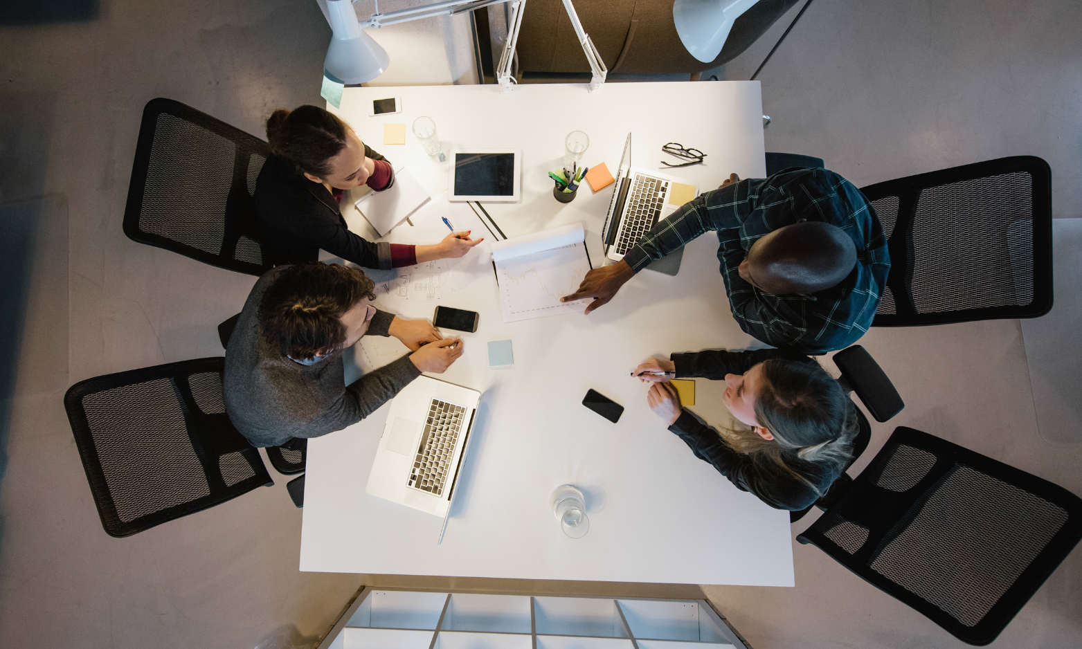 four business people at desk discussing a project